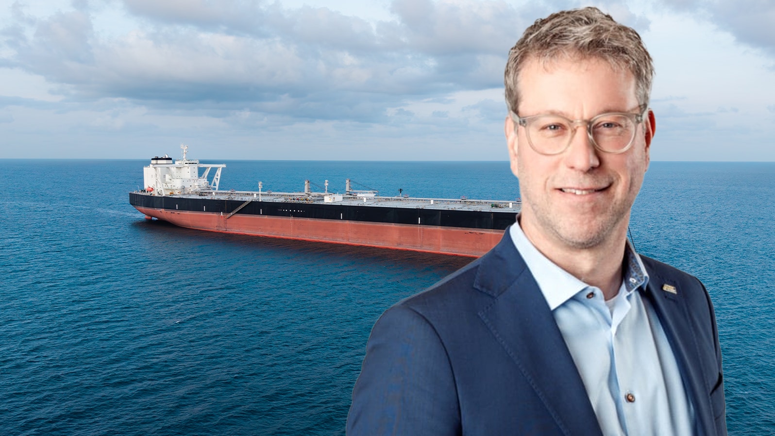 Porträtt av en Anders Hermansson från Svensk sjöfart. Han har glasögon och i bakgrunden ser man ett lastfartyg på havet.