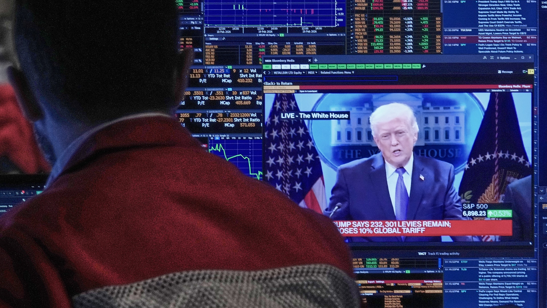 Person tittar på finansiella marknadsdata och nyhetsöverföring på datorskärmar