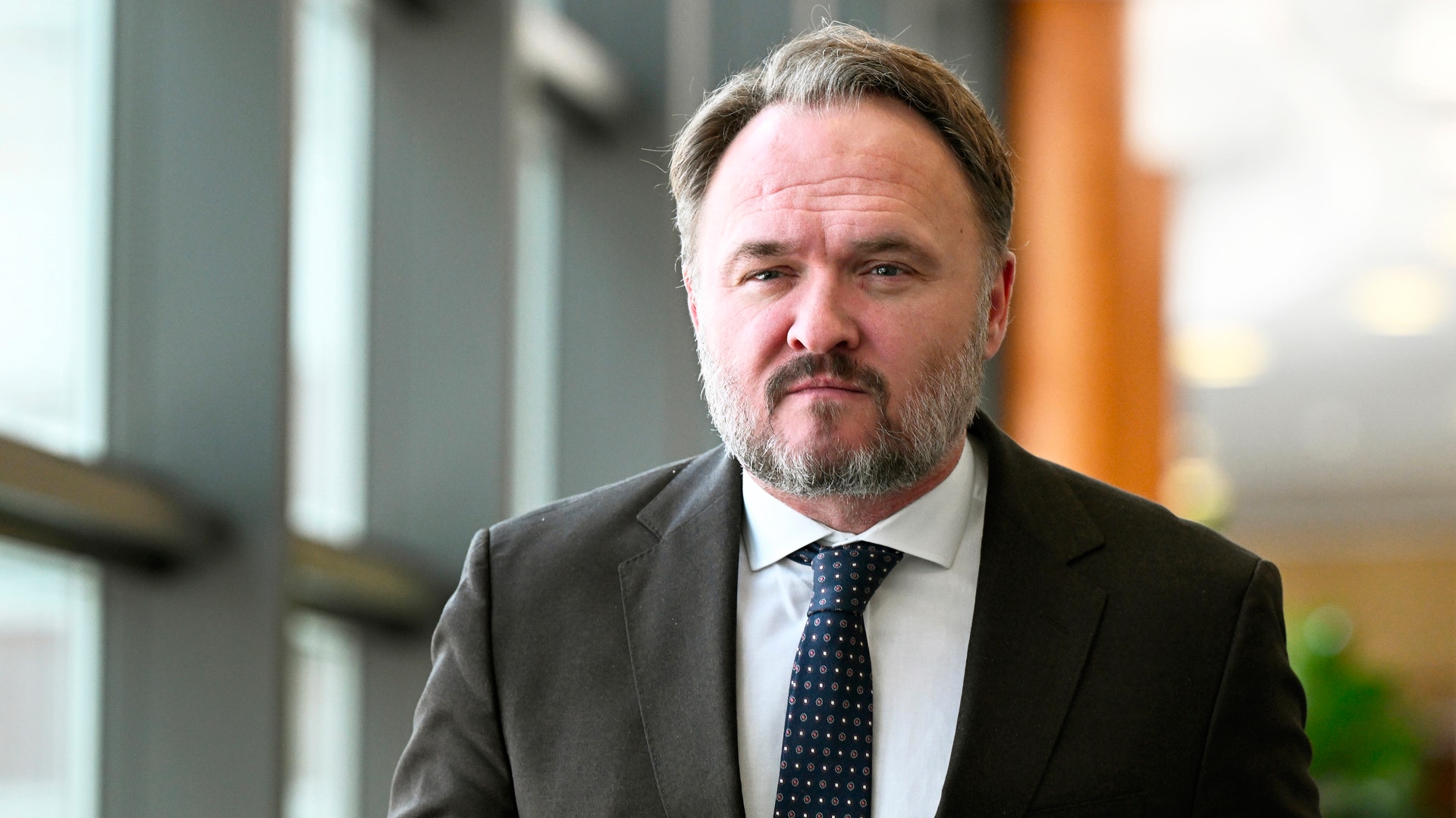 Porträtt av en man i kostym och slips i en modern kontorsmiljö