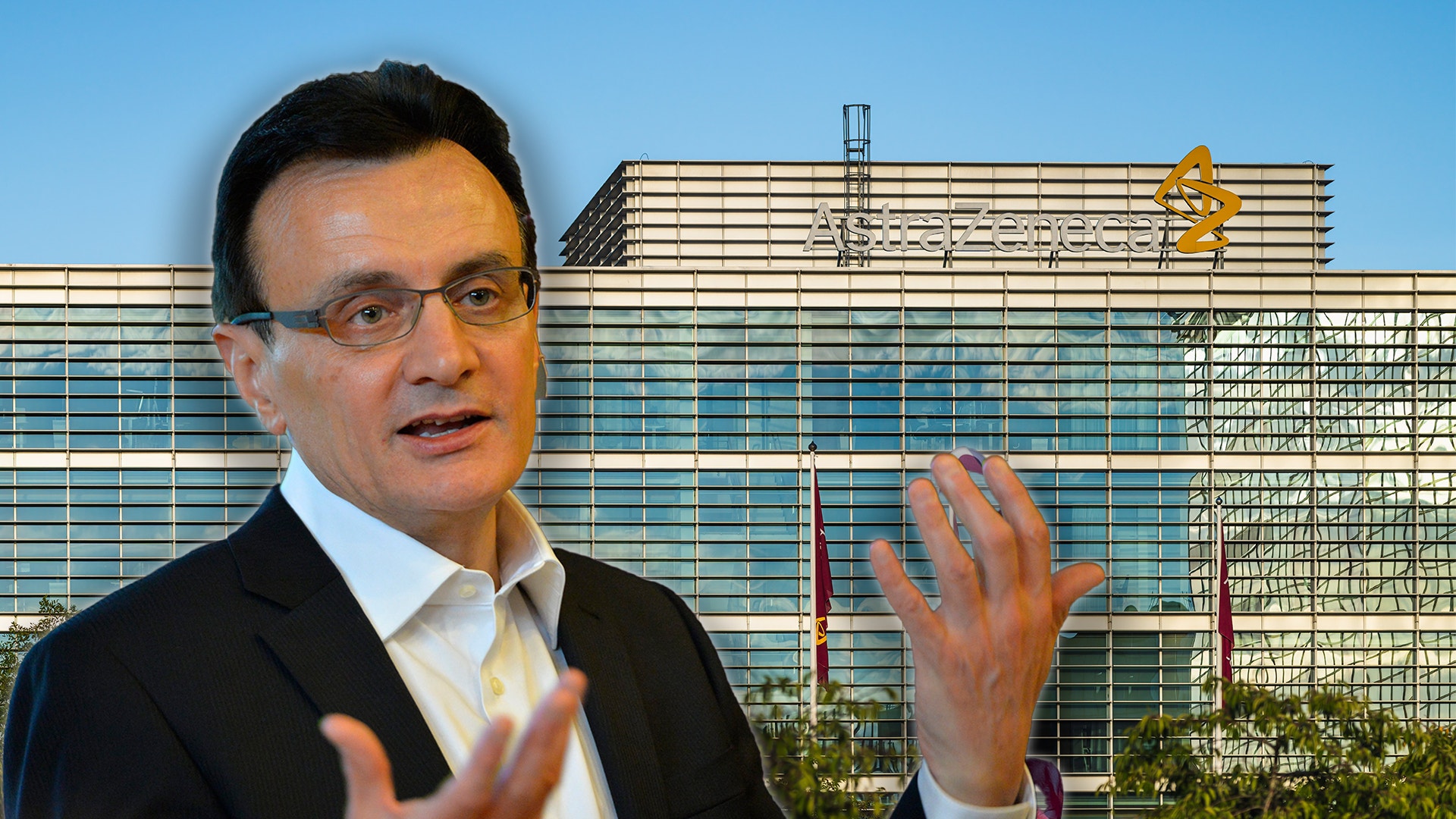 Man i kostym och glasögon gestikulerar framför en modern kontorsbyggnad.