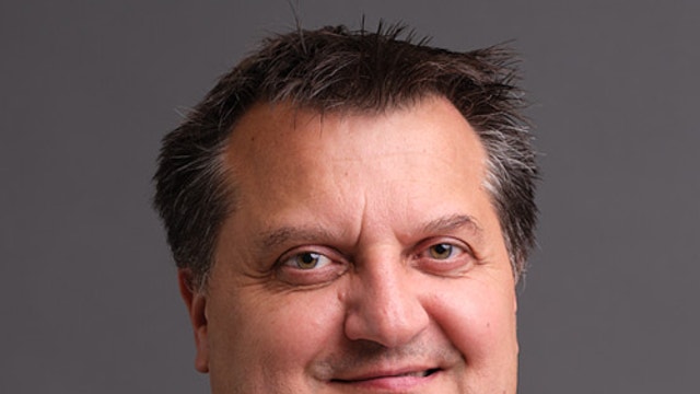 Porträtt av en man i mörk kavaj och vit skjorta mot grå bakgrund