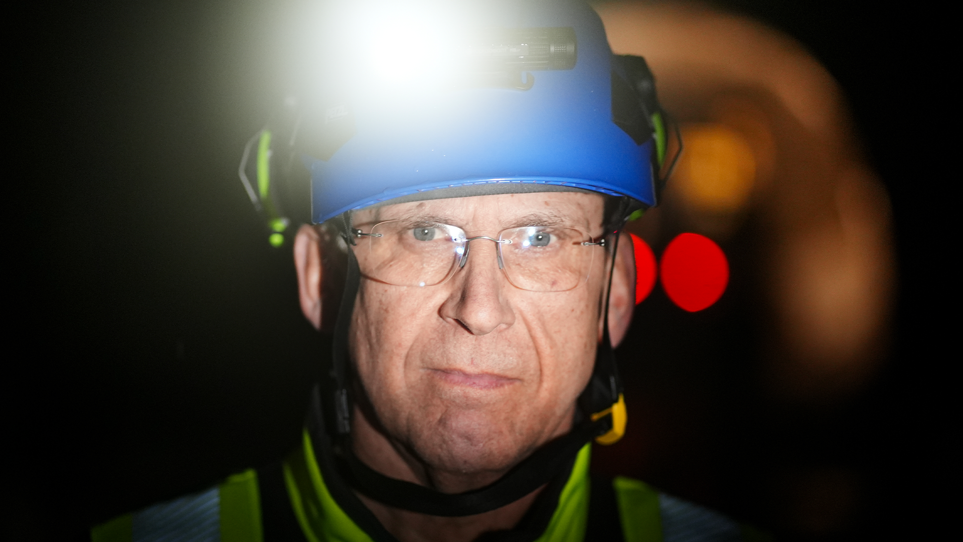 Person med blå pannlampa och säkerhetsutrustning i mörker