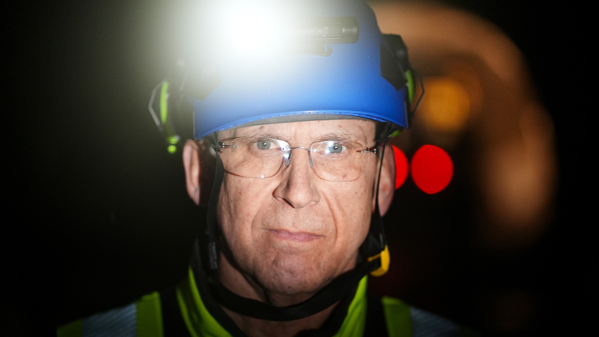 Person med blå pannlampa och säkerhetsutrustning i mörker