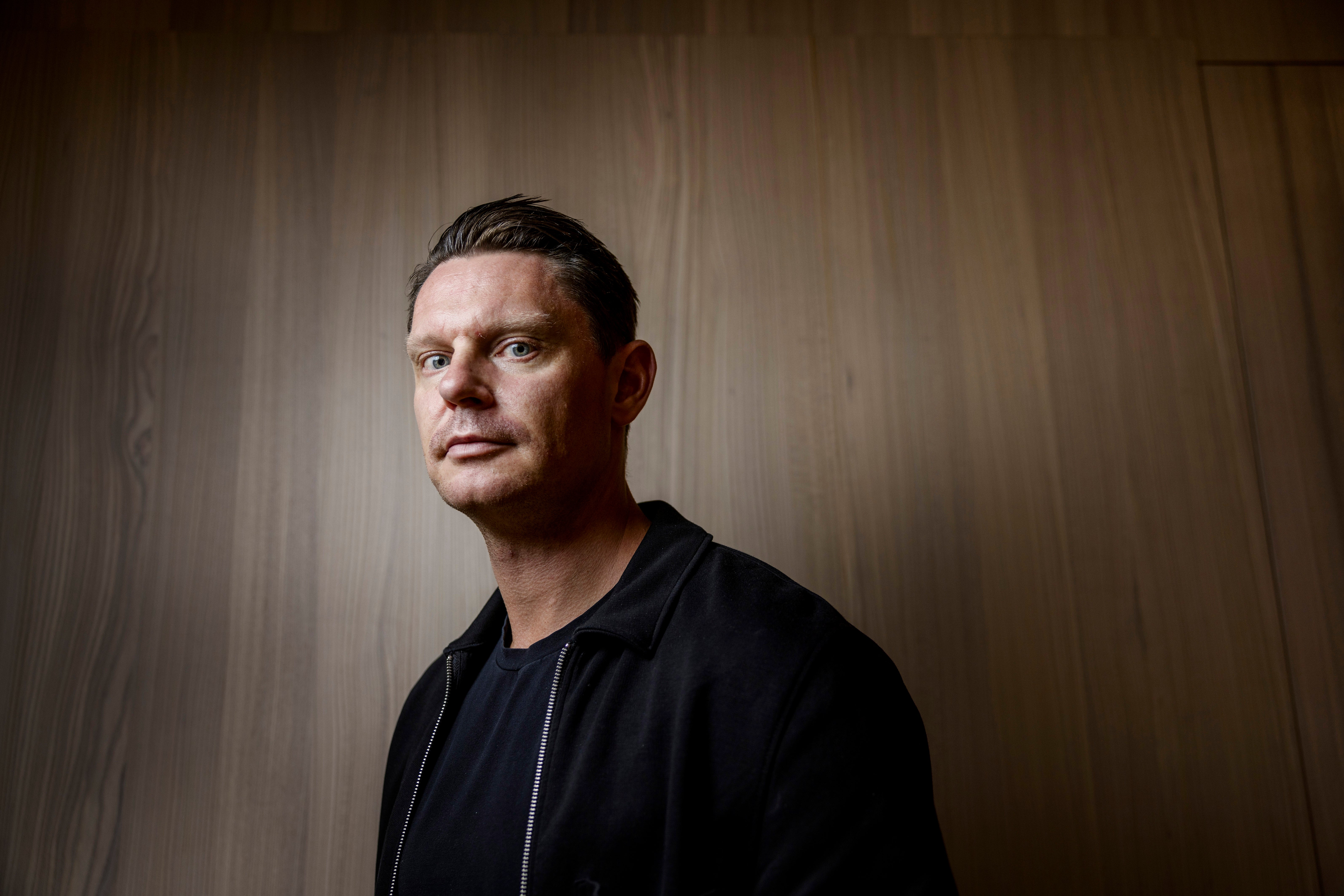 Porträttfoto av en David Sandström (marknadschef Klarna) i svart jacka mot en trävägg.