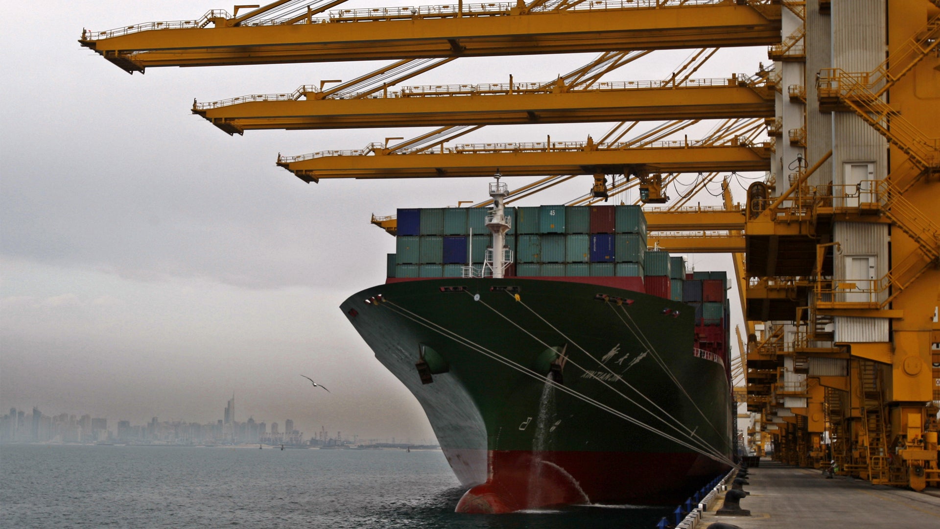 Lastfartyg lastat med containrar vid containerhamn med gula kranar