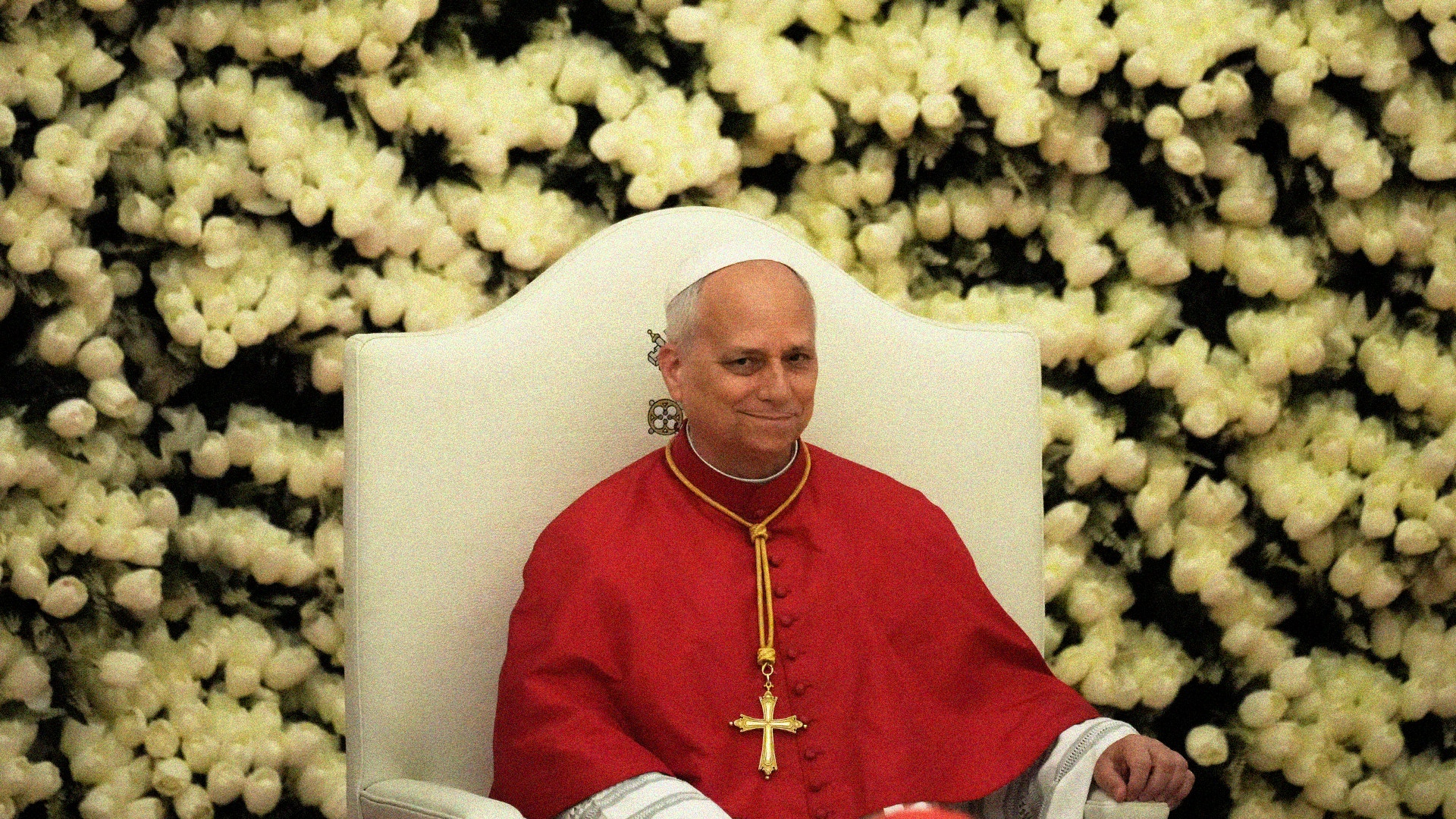 Påven sitter i en vit stol och bär röd dräkt med guldkors.