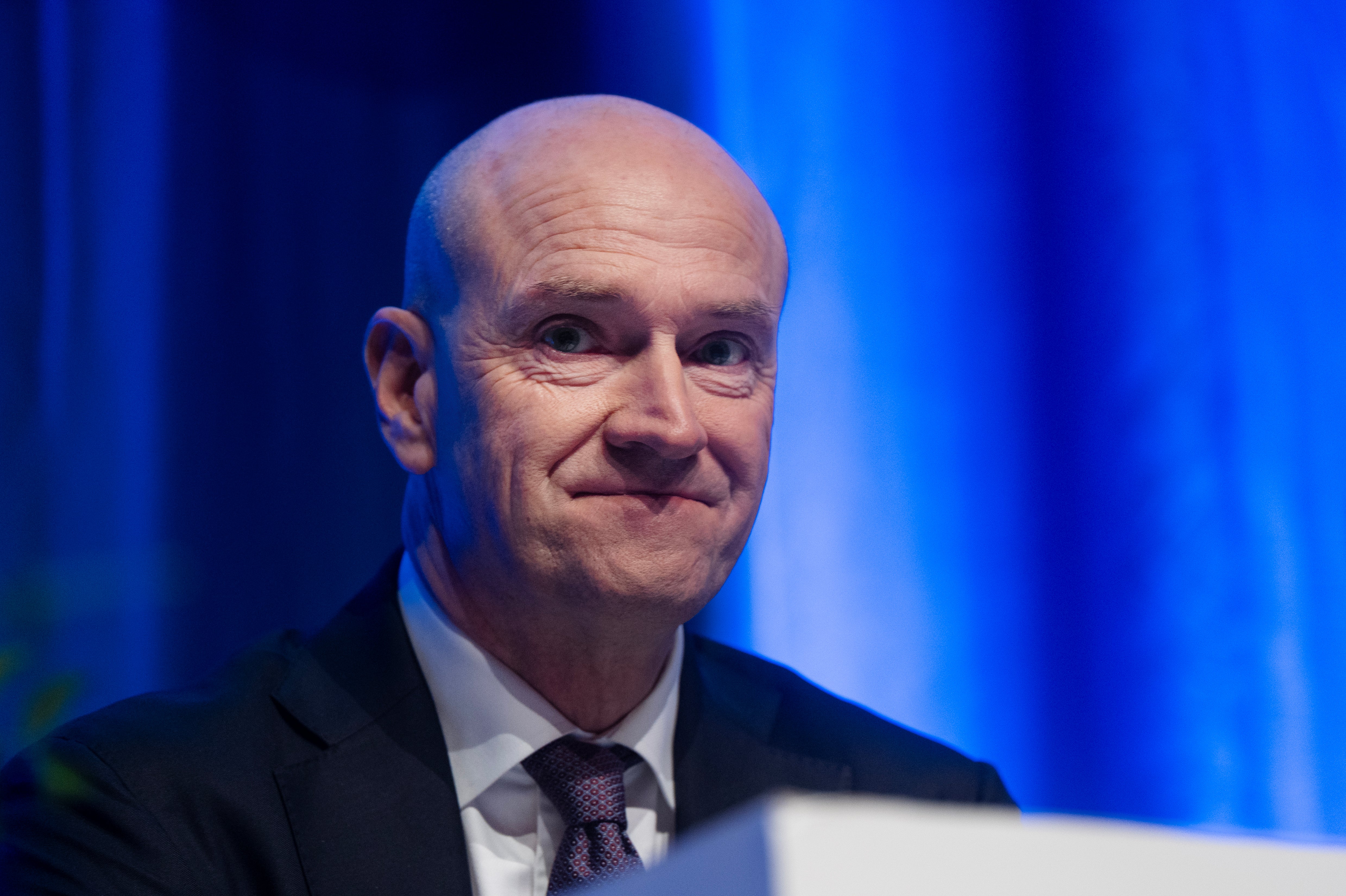 En man i kostym och slips framför en blå bakgrund