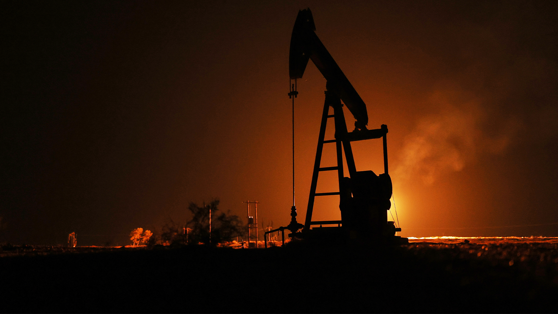 Oljepump i siluett mot orange himmel vid skymning