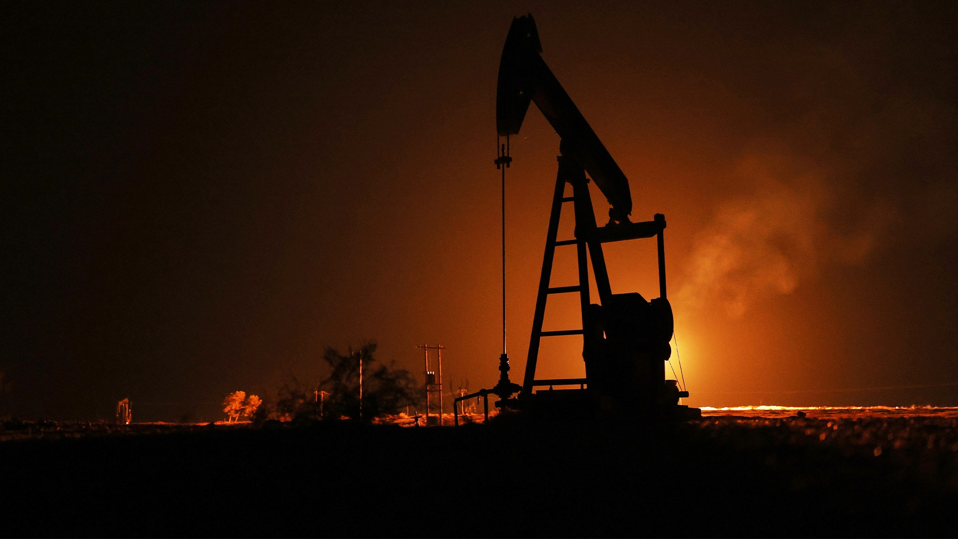 Oljepump i siluett mot orange himmel vid skymning