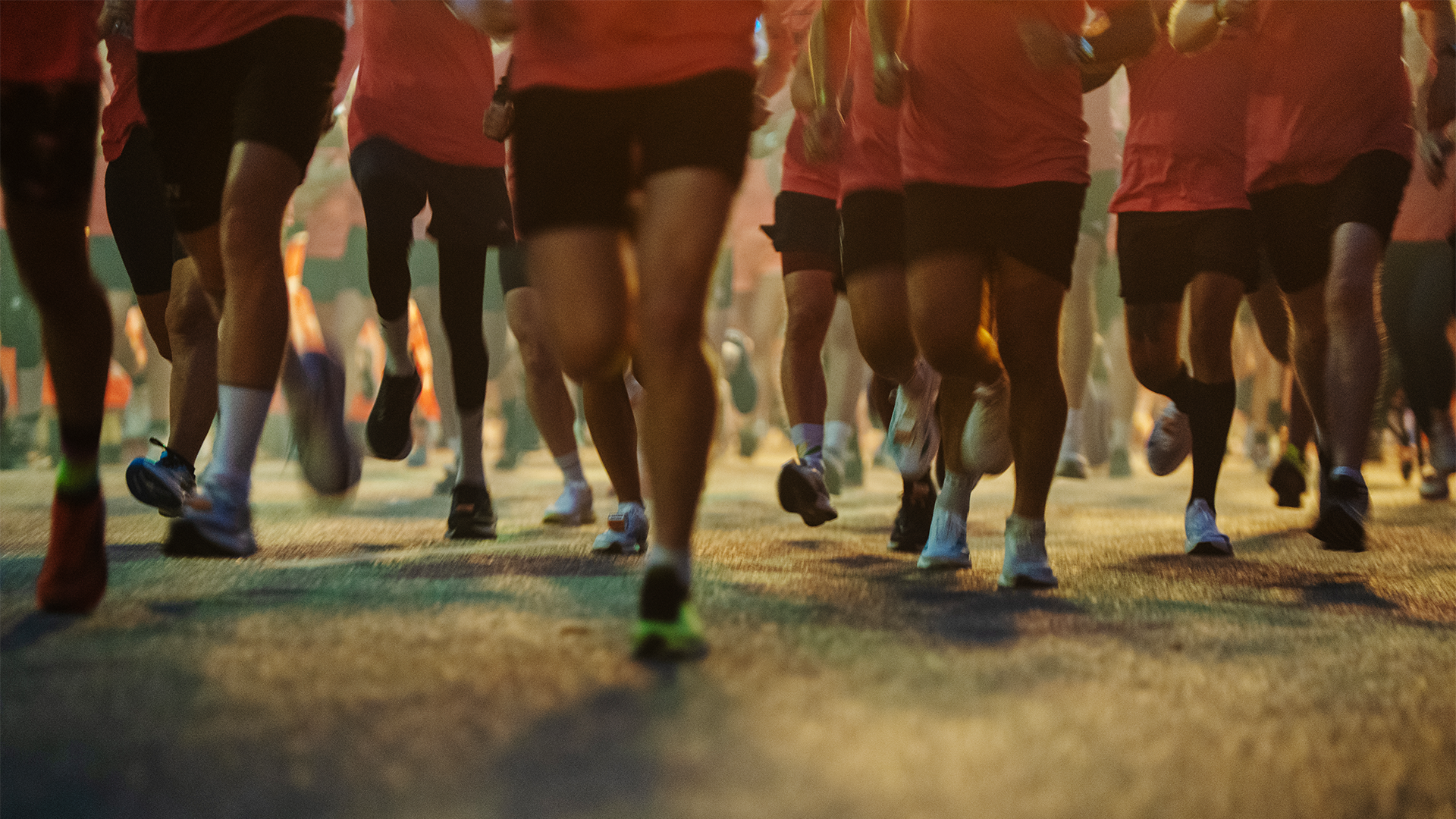 Löpare springer i ett gatuupplyst midnattslopp. Alla i färgglada löparskor.  
