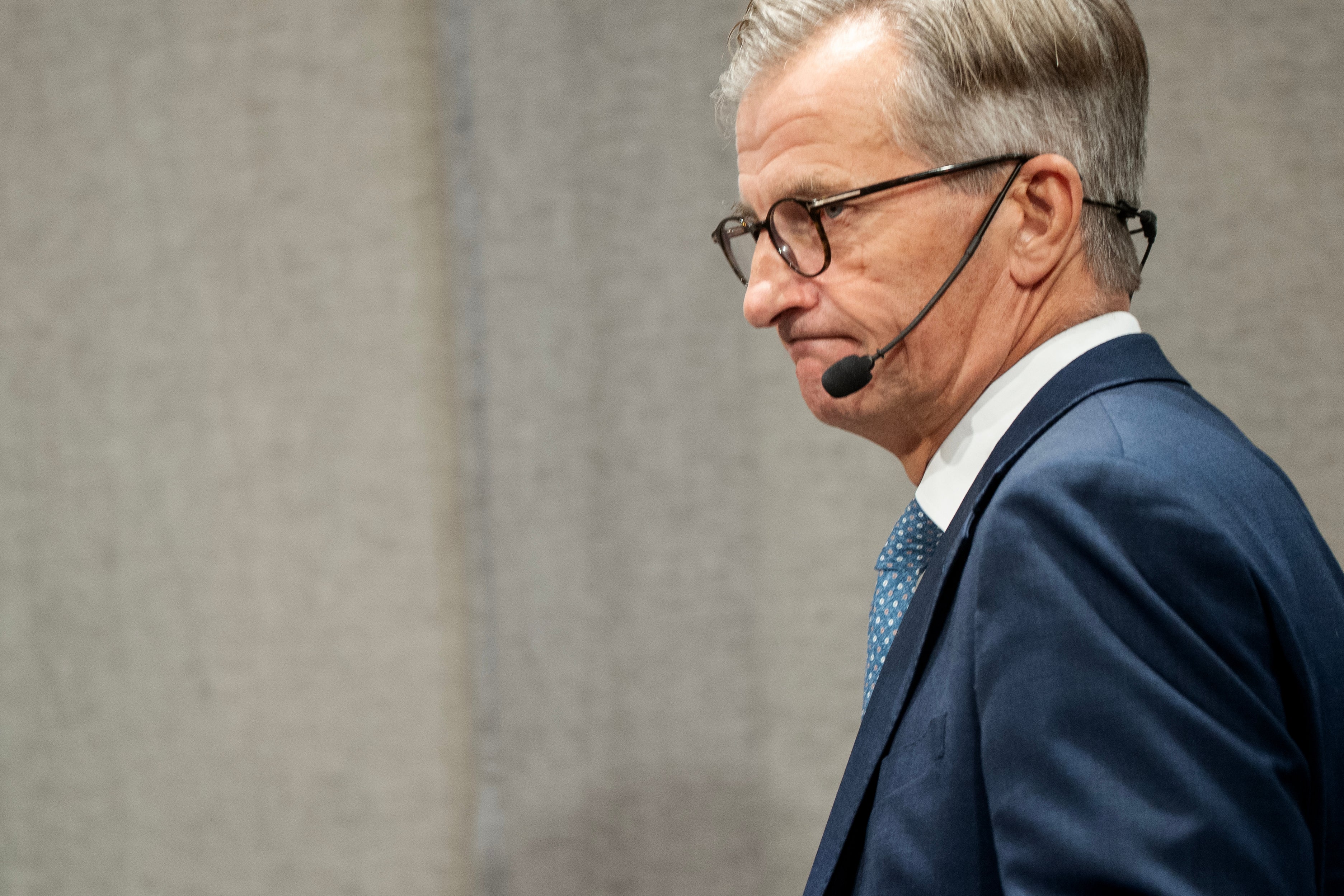 Man i mörk kostym med headset-mikrofon, fotograferad i profil under en presentation eller föreläsning.