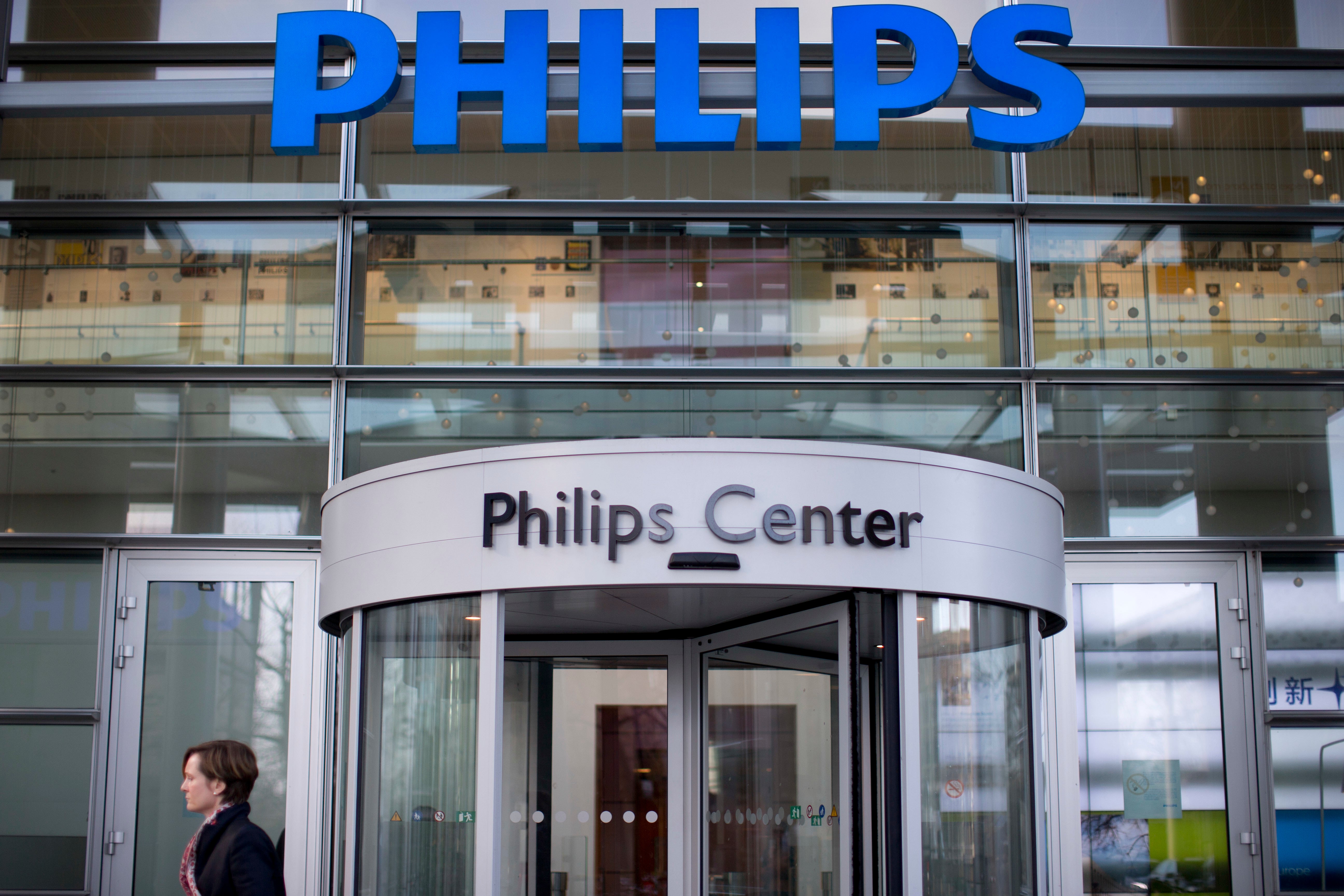 Fasaden på Philips Center med blå Philips-logotyp på taket och en rund glassad entrédörr. En person i svart jacka står framför byggnaden.