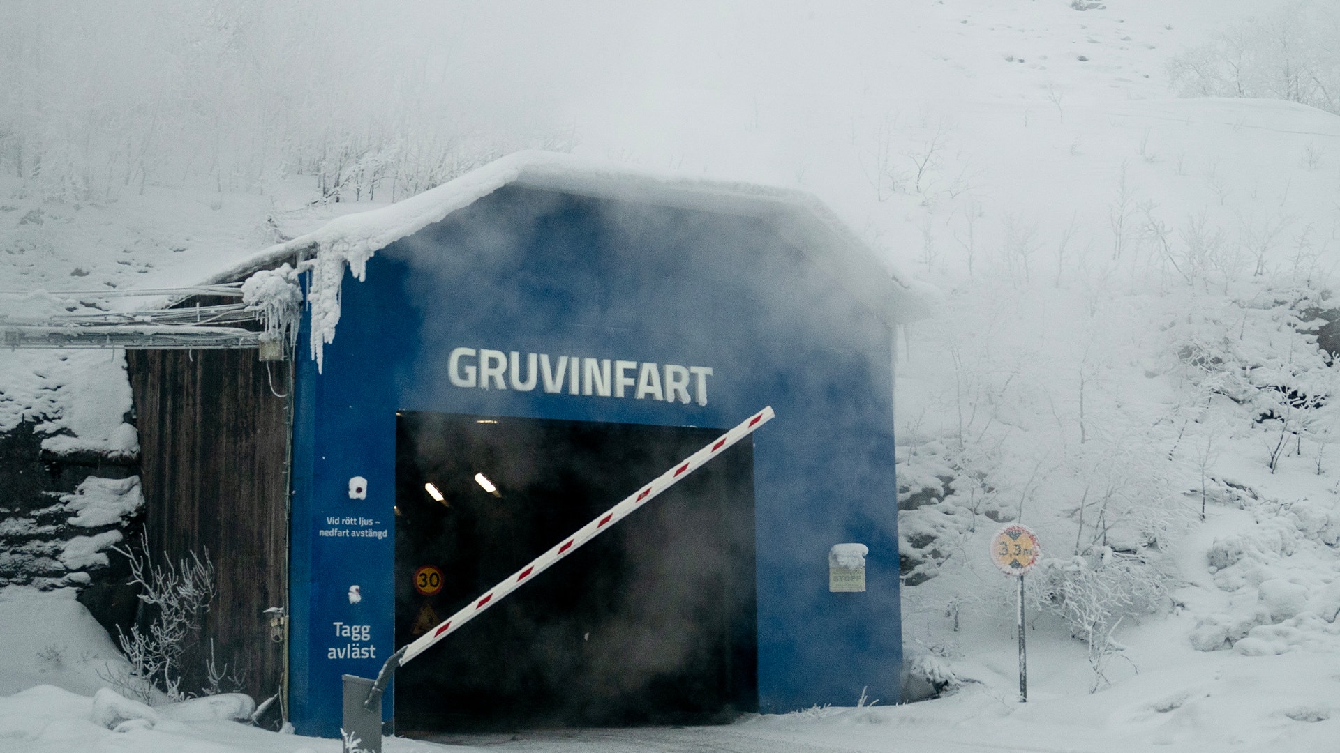 Blå gruvingang märkt "GRUVINFART" omgiven av snö och vinterlandskap