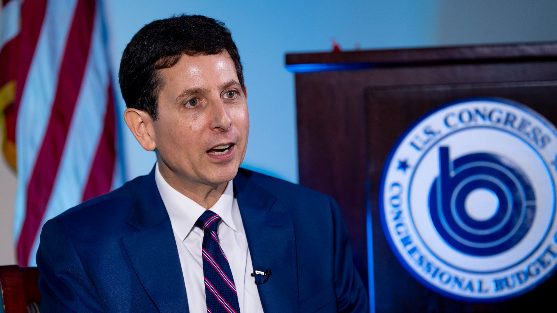 Phillip Swagel talar framför den amerikanska flaggan och ett kongressemblem.