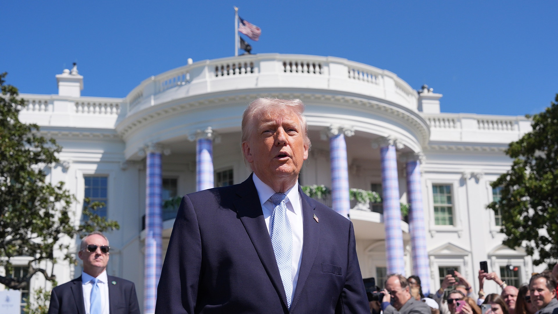 Man i mörk kostym framför Vita huset