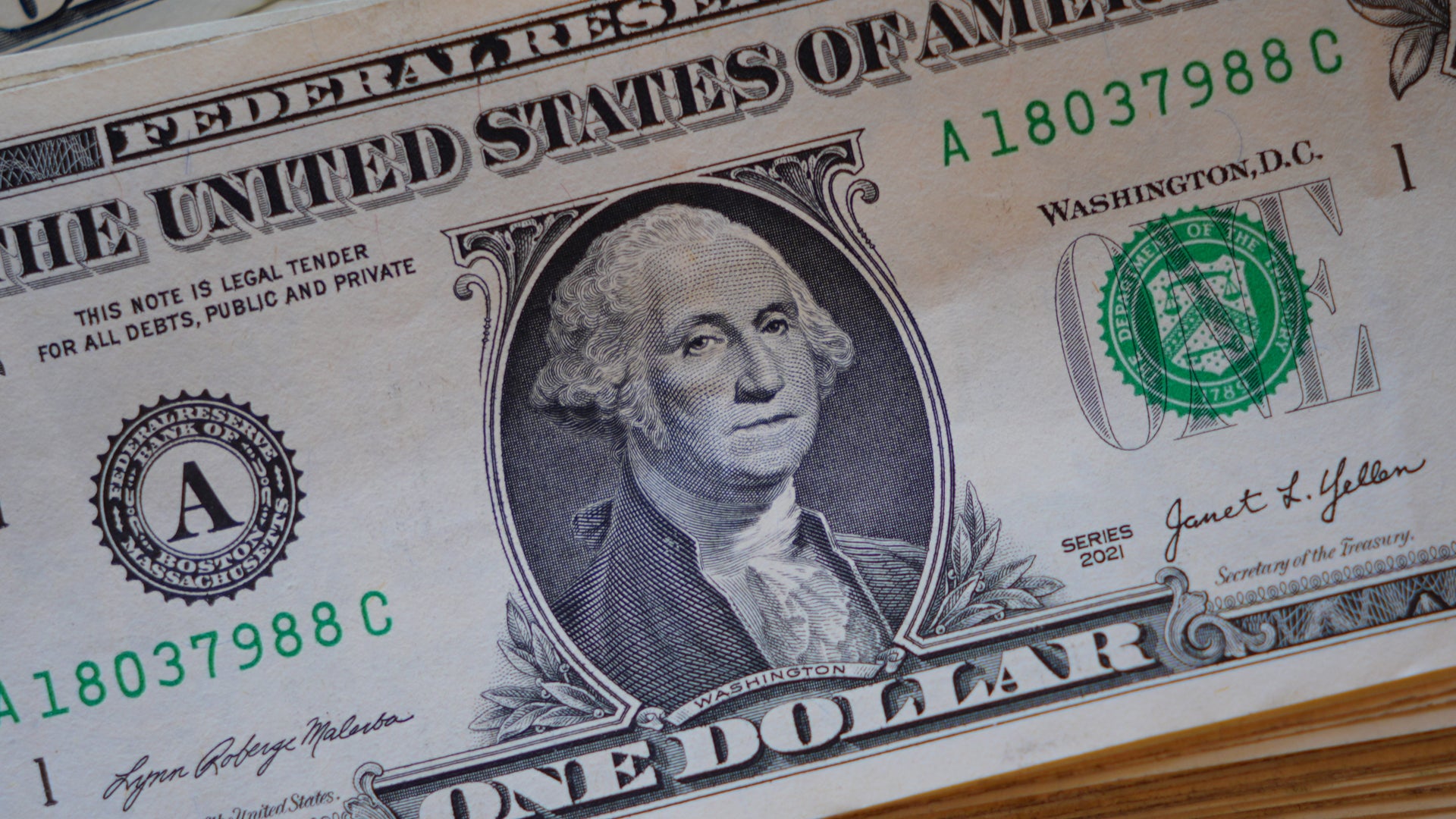 Närbildsfotografi av en amerikansk en-dollarsedel med George Washingtons porträtt och officiella märkningar.