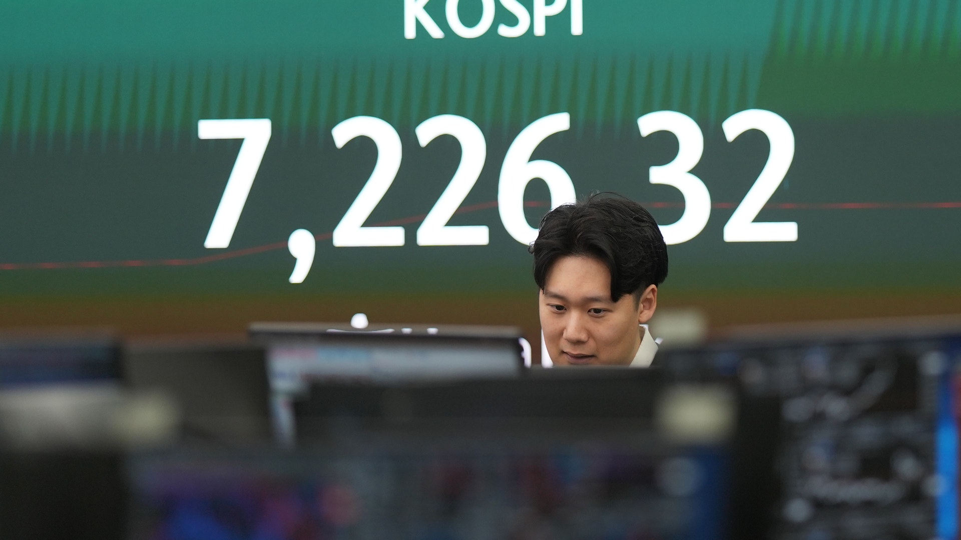 Man sitter framför en skärm som visar KOSPI-aktieindex med värdet 7,226.32