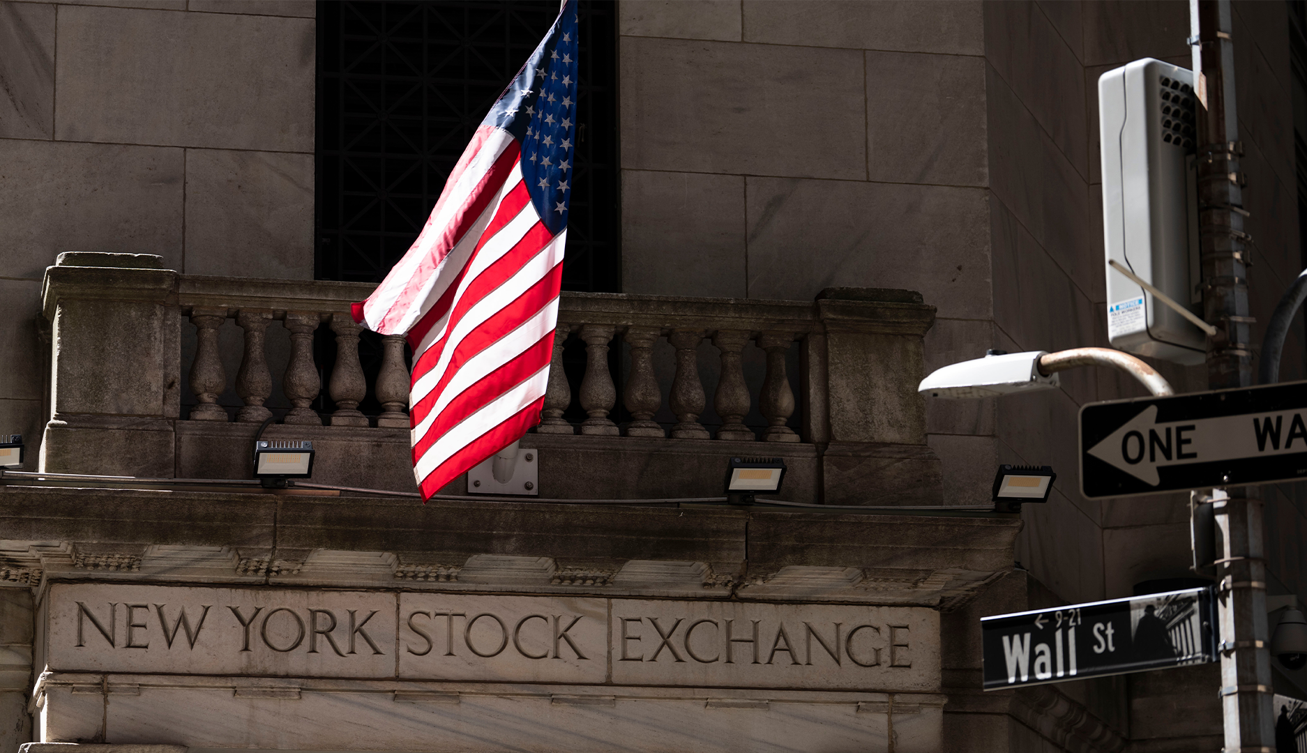 Fasaden till New York Stock Exchange på Wall Street, med en amerikansk flagga.