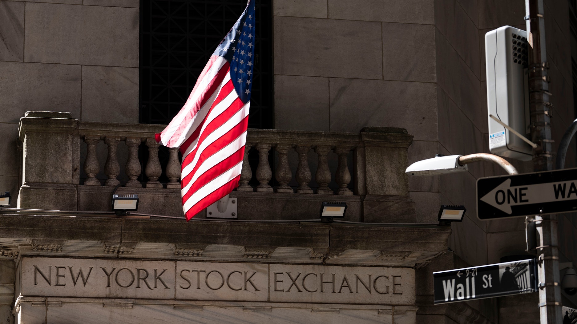 Fasaden till New York Stock Exchange på Wall Street, med en amerikansk flagga.
