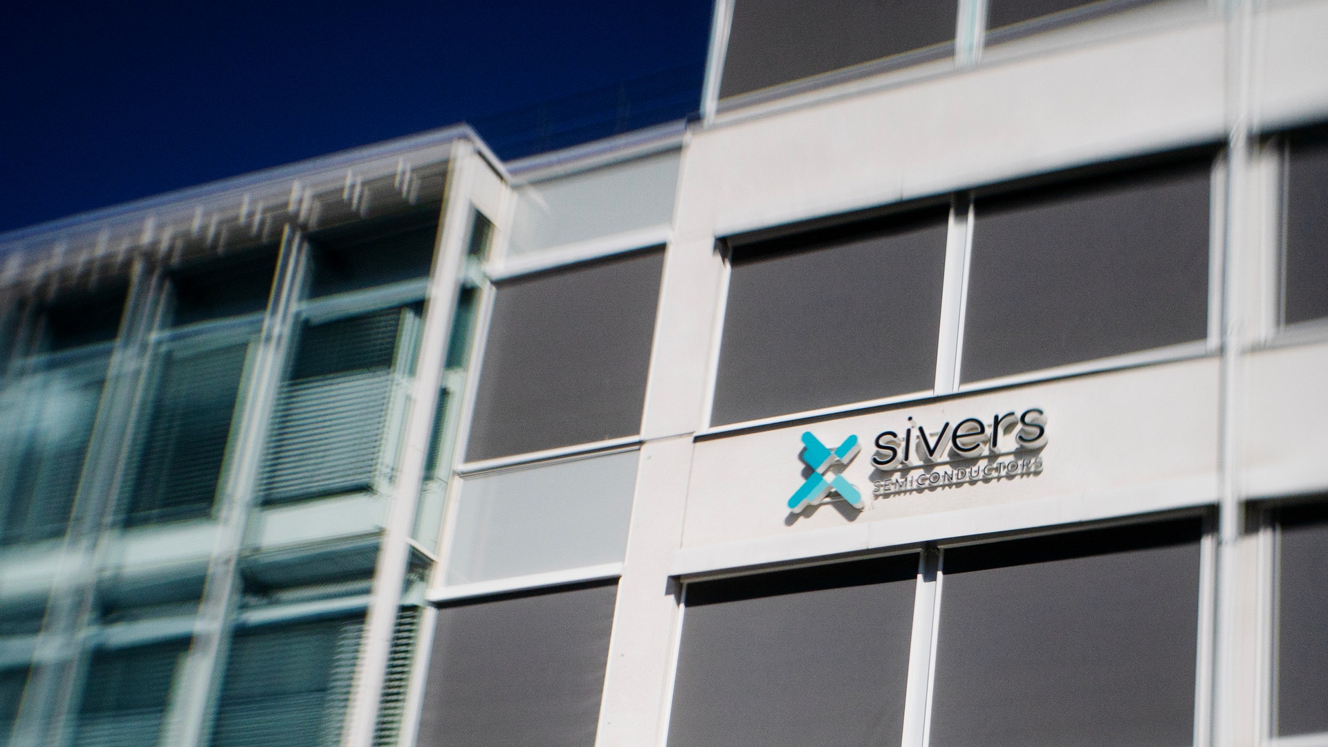 Moderna kontorsbyggnad med Sivers-logotyp på vit vägg