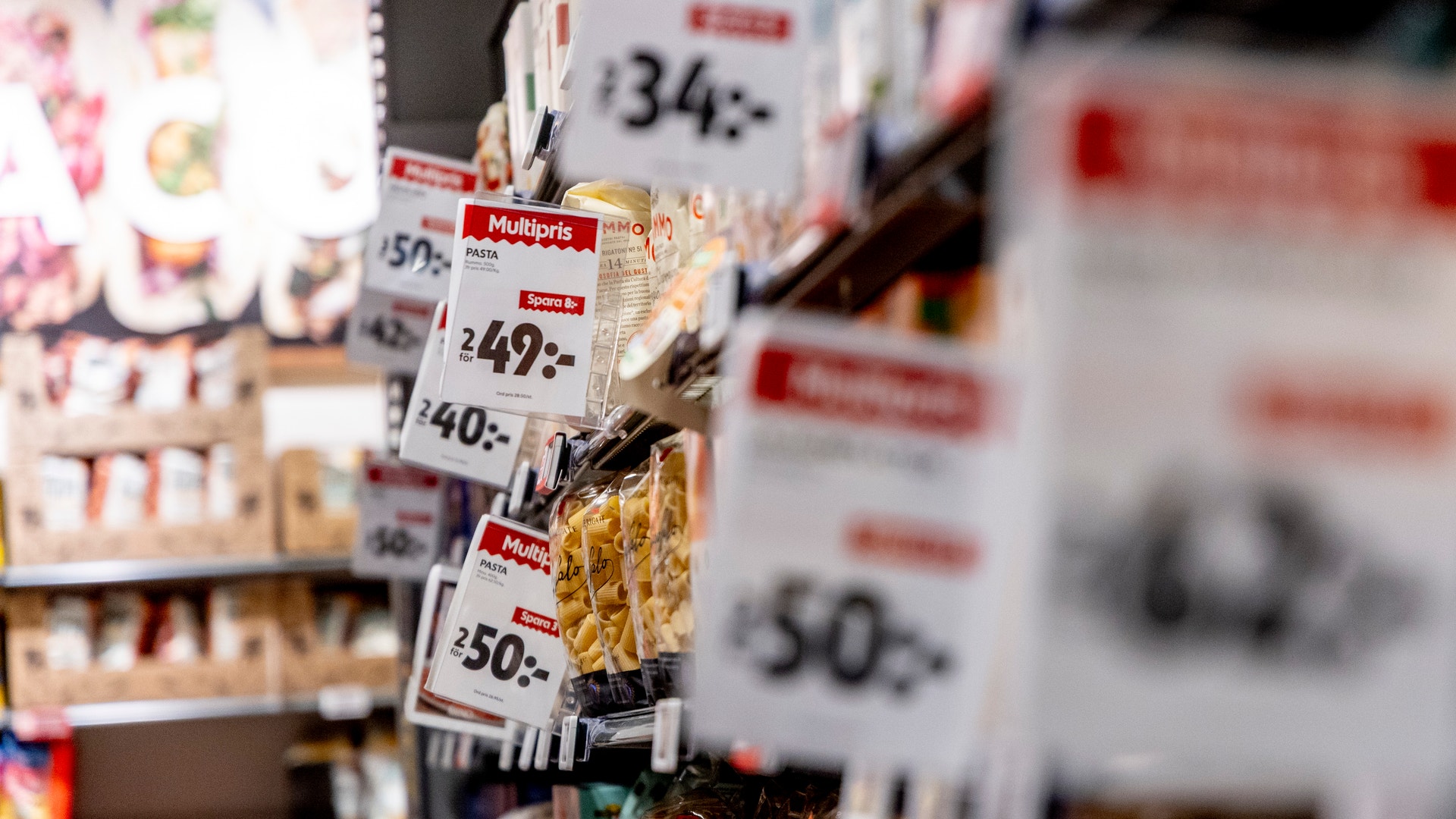 Närbild av matvaror på en butikshylla med röda prisetikett som visar priser på svenska kronor.