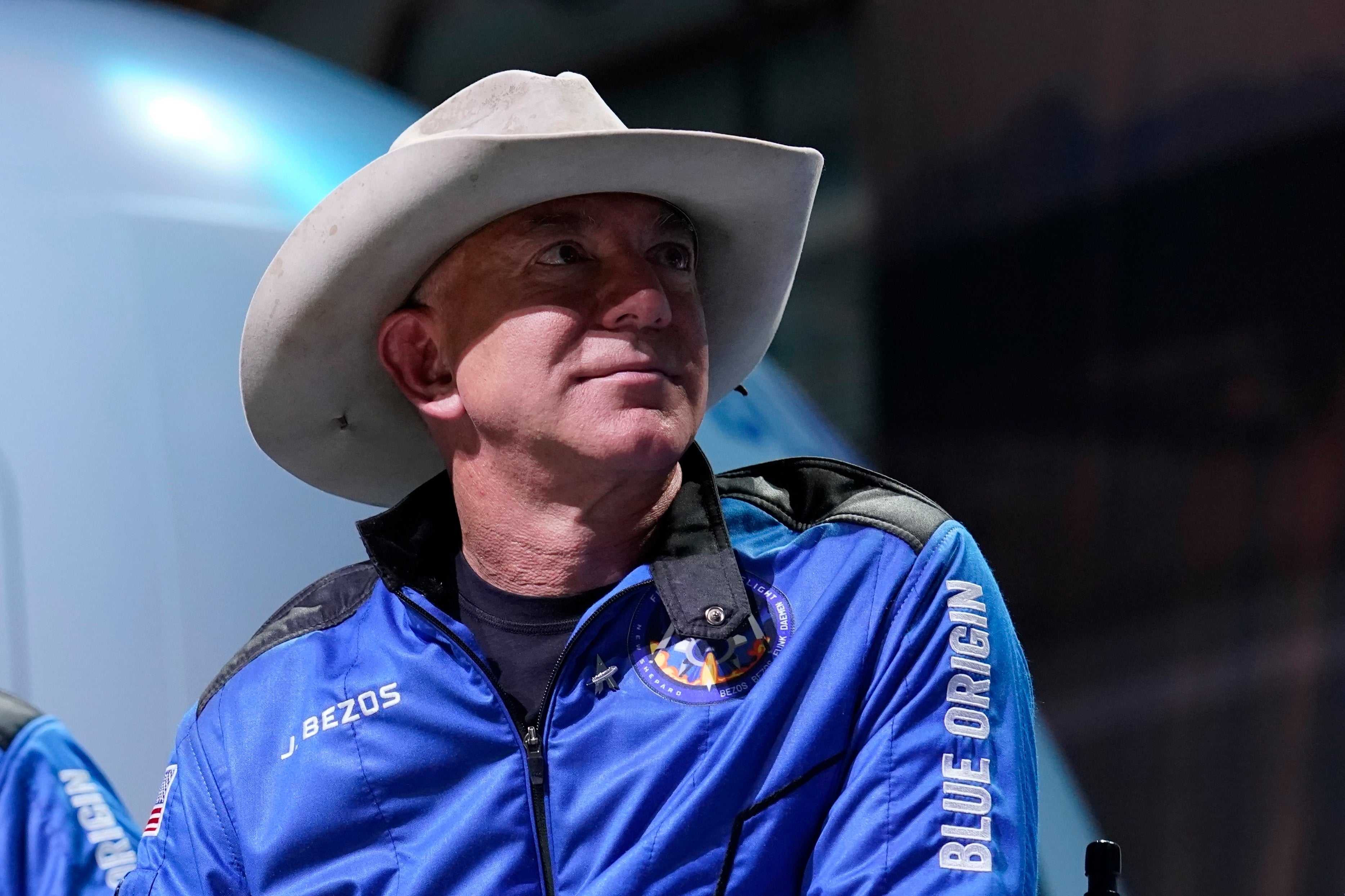 Man i vit cowboyhatt och blå jacka vid ett event.