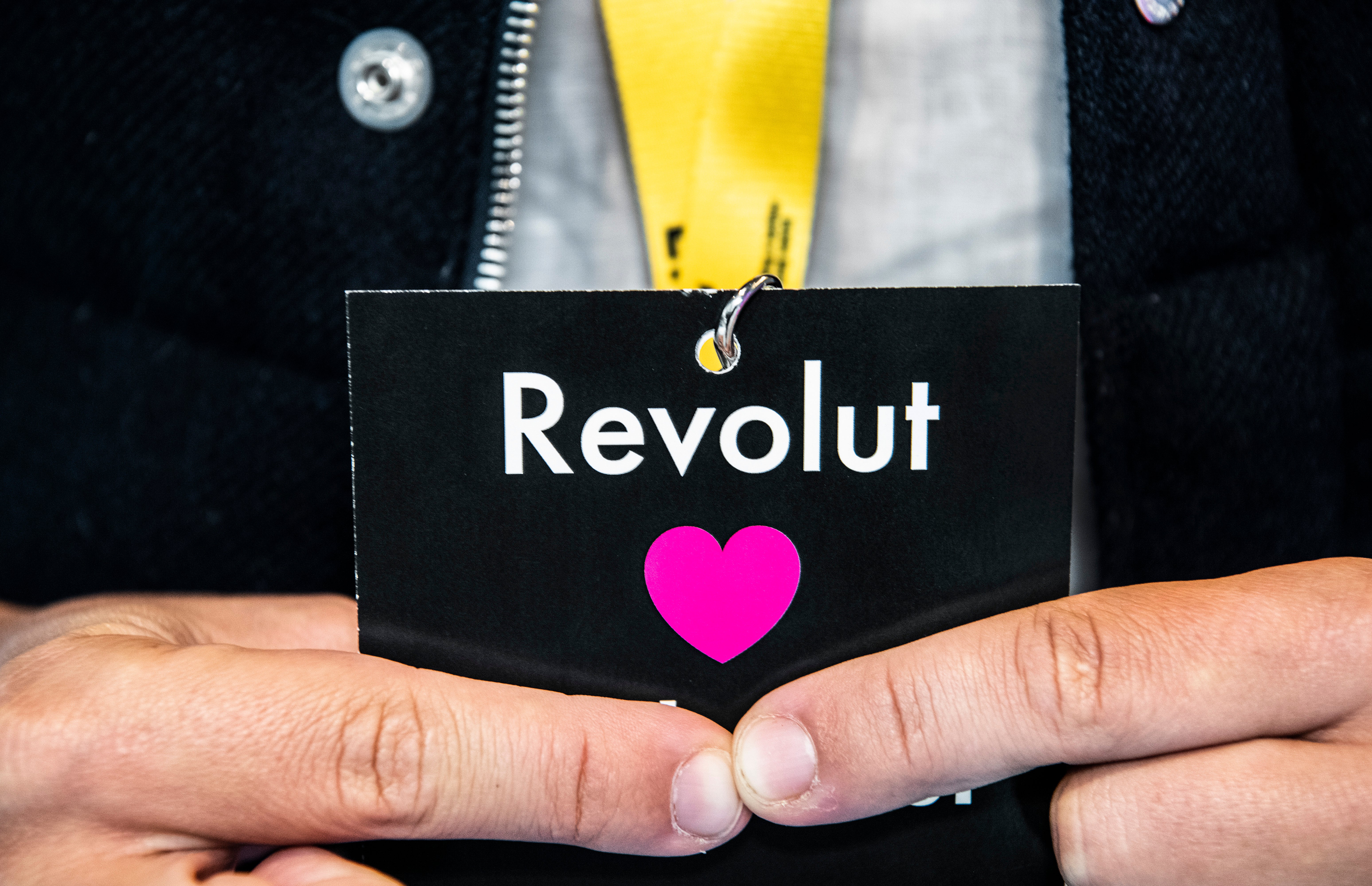 Hand som håller ett svart ID-kort med Revolut-logotypen och ett rosa hjärta