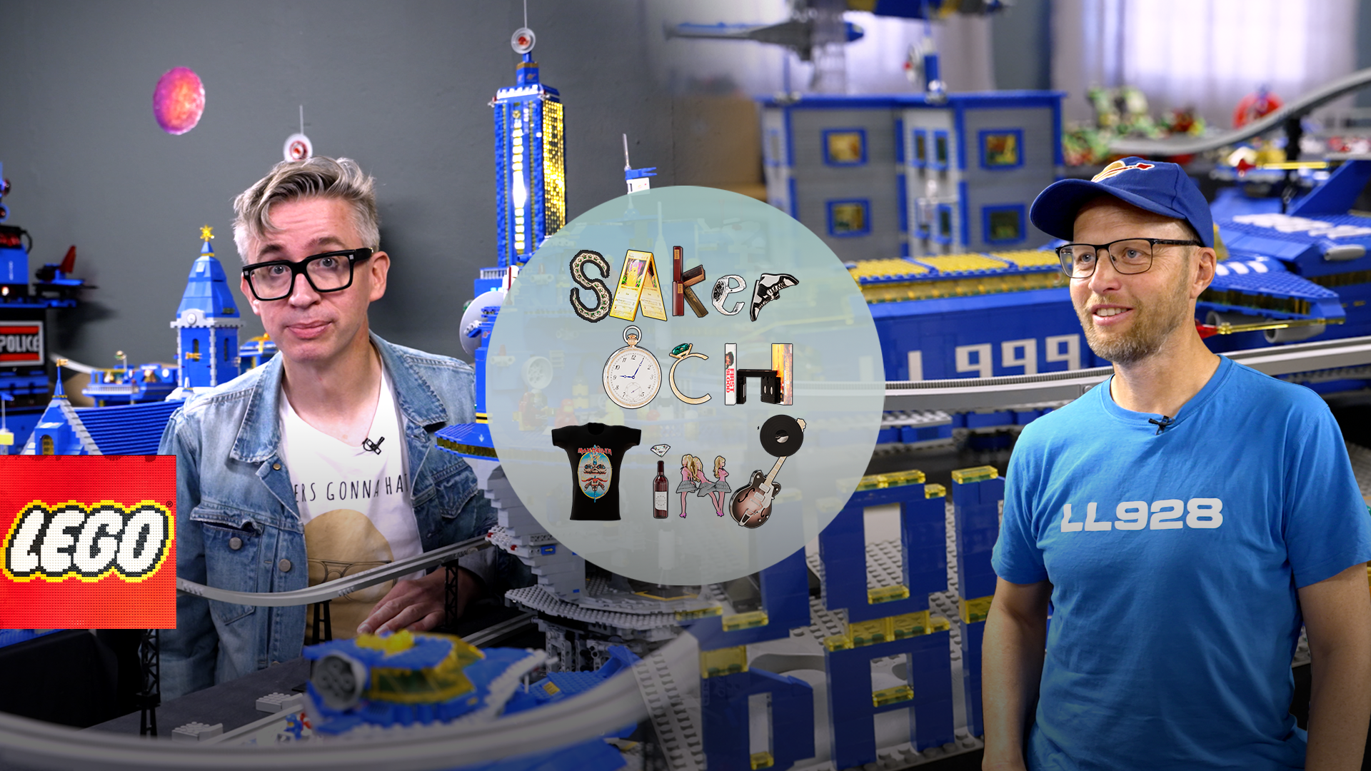 Två personer visar upp en vit cirkulär skiva med LEGO-minifigur-tillbehör framför en stor blå LEGO-konstruktion.