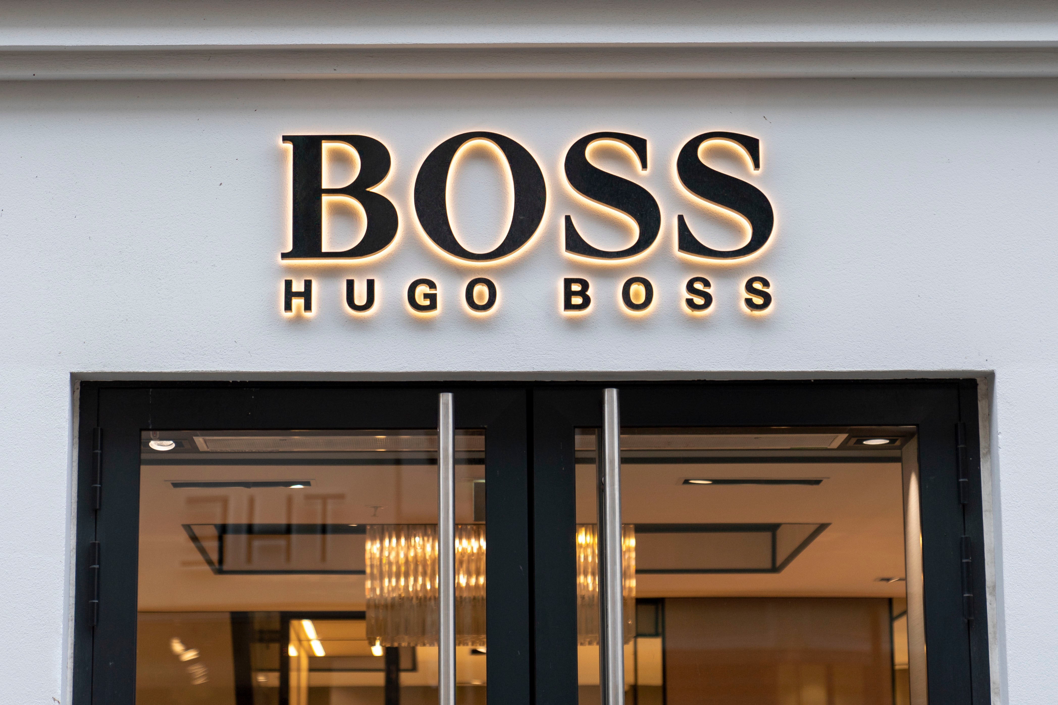 Butiksfasad för Hugo Boss med guldtext på vit vägg och svarta glasdörrar.