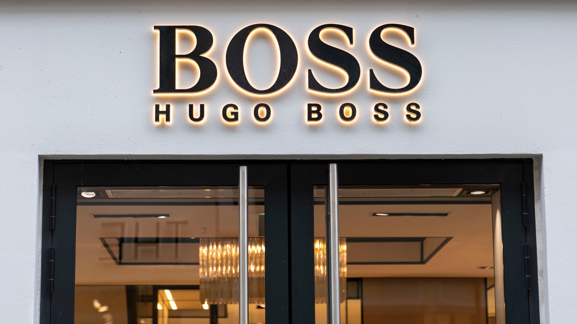 Butiksfasad för Hugo Boss med guldtext på vit vägg och svarta glasdörrar.