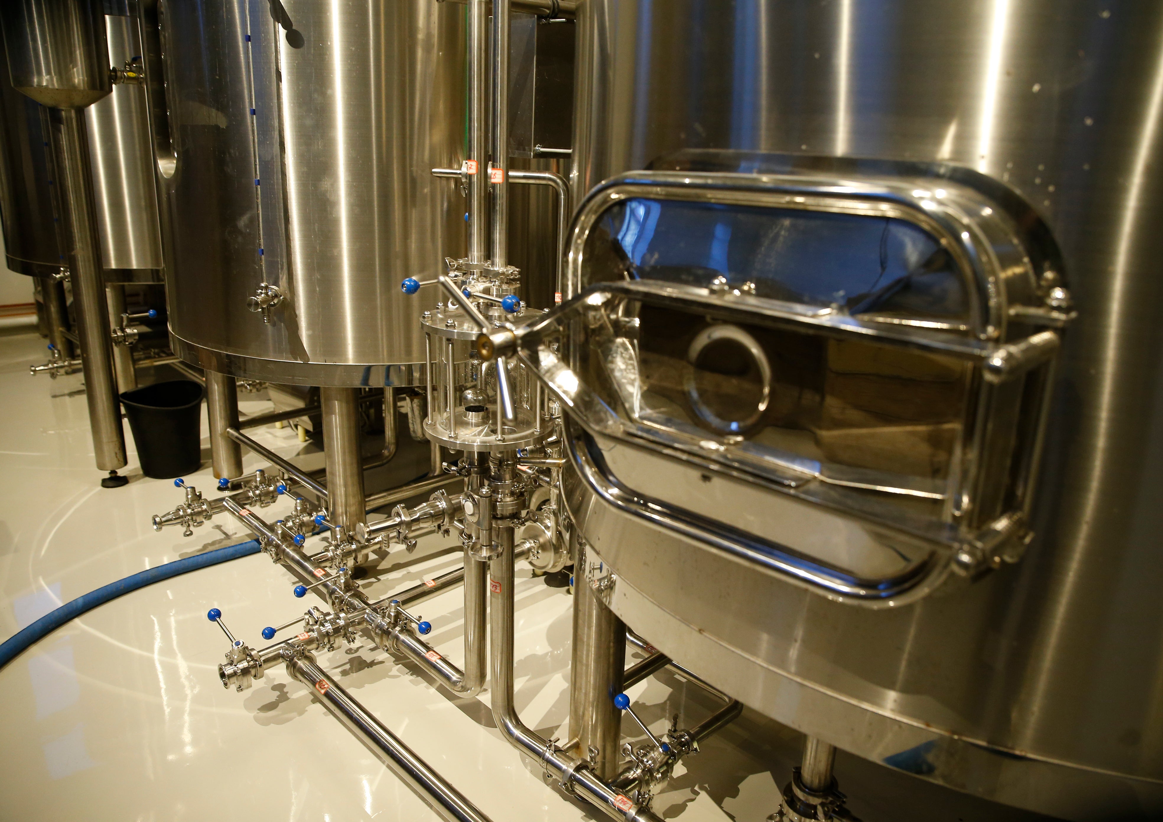 Industriell rostfritt stål bryggeriutrustning med stora lagertankar och rörsystem.