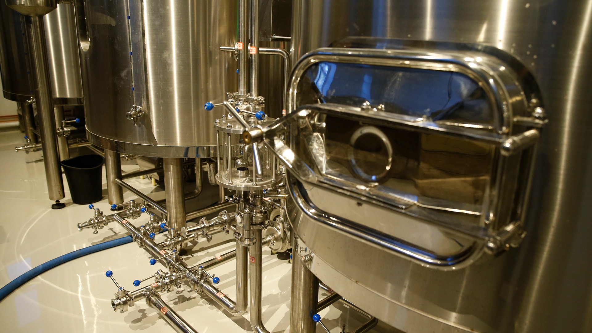 Industriell rostfritt stål bryggeriutrustning med stora lagertankar och rörsystem.