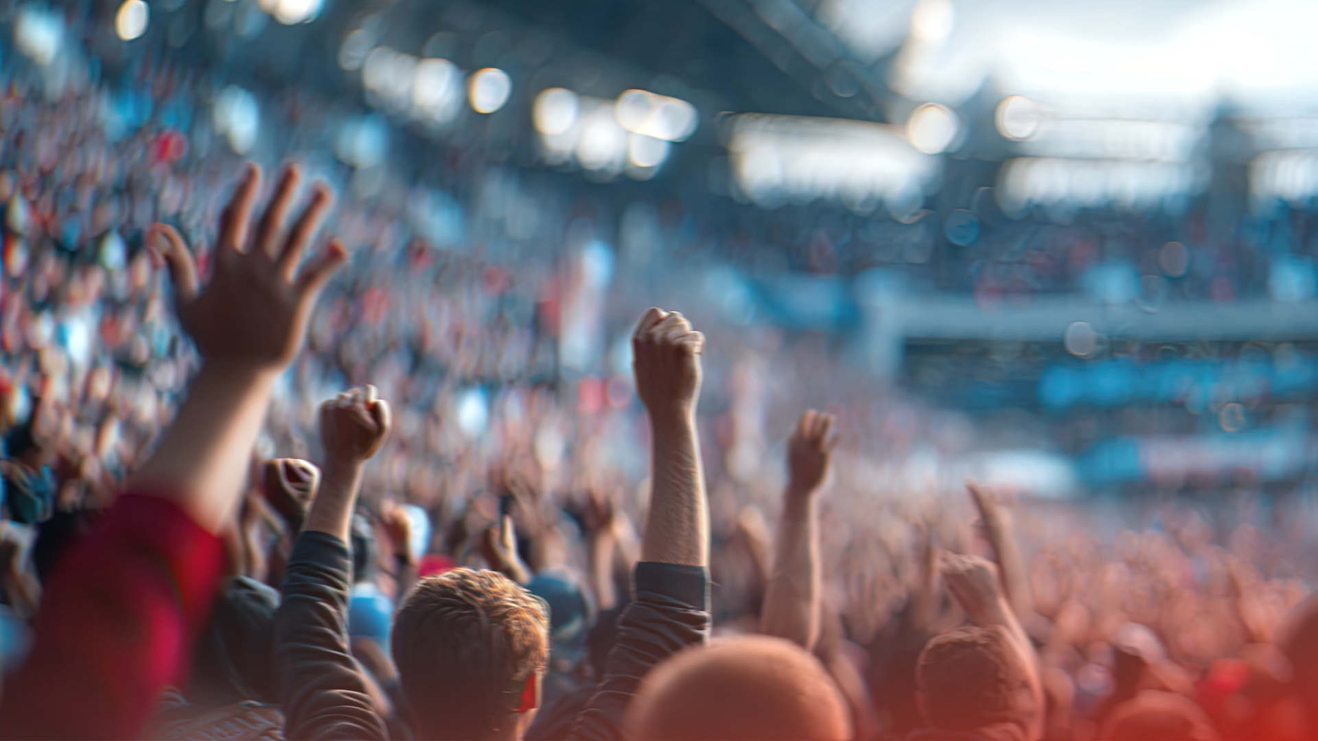 Folkmassa med upphöjda händer och nävar på ett stort stadion under ett evenemang.