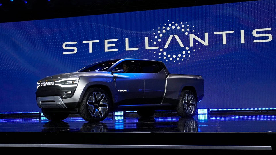 En modern elektrisk pickup-truck presenterad på en scen med Stellantis-logotyp i bakgrunden