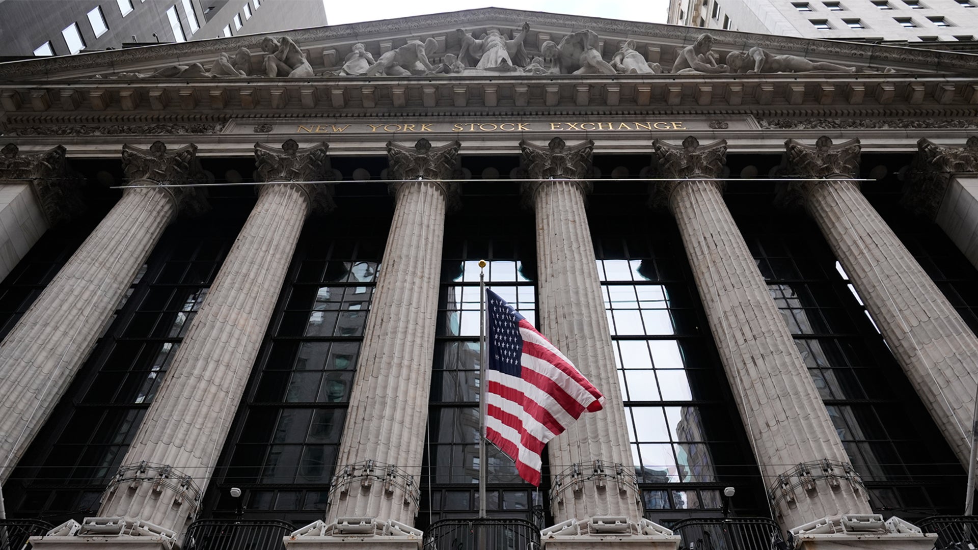 Fasaden på New York Stock Exchange med klassiska kolonner och amerikansk flagga
