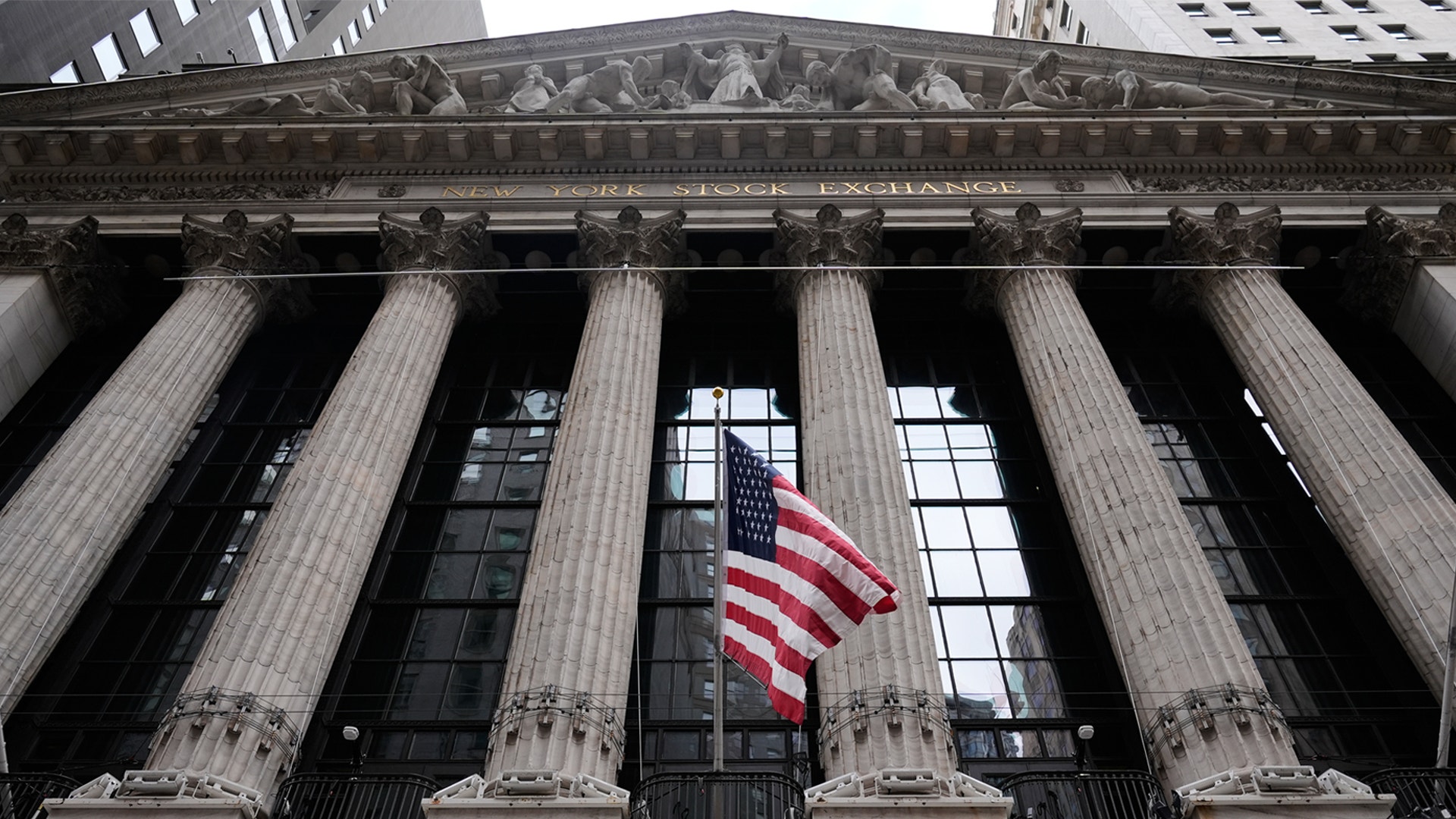 Fasaden på New York Stock Exchange med klassiska kolonner och amerikansk flagga