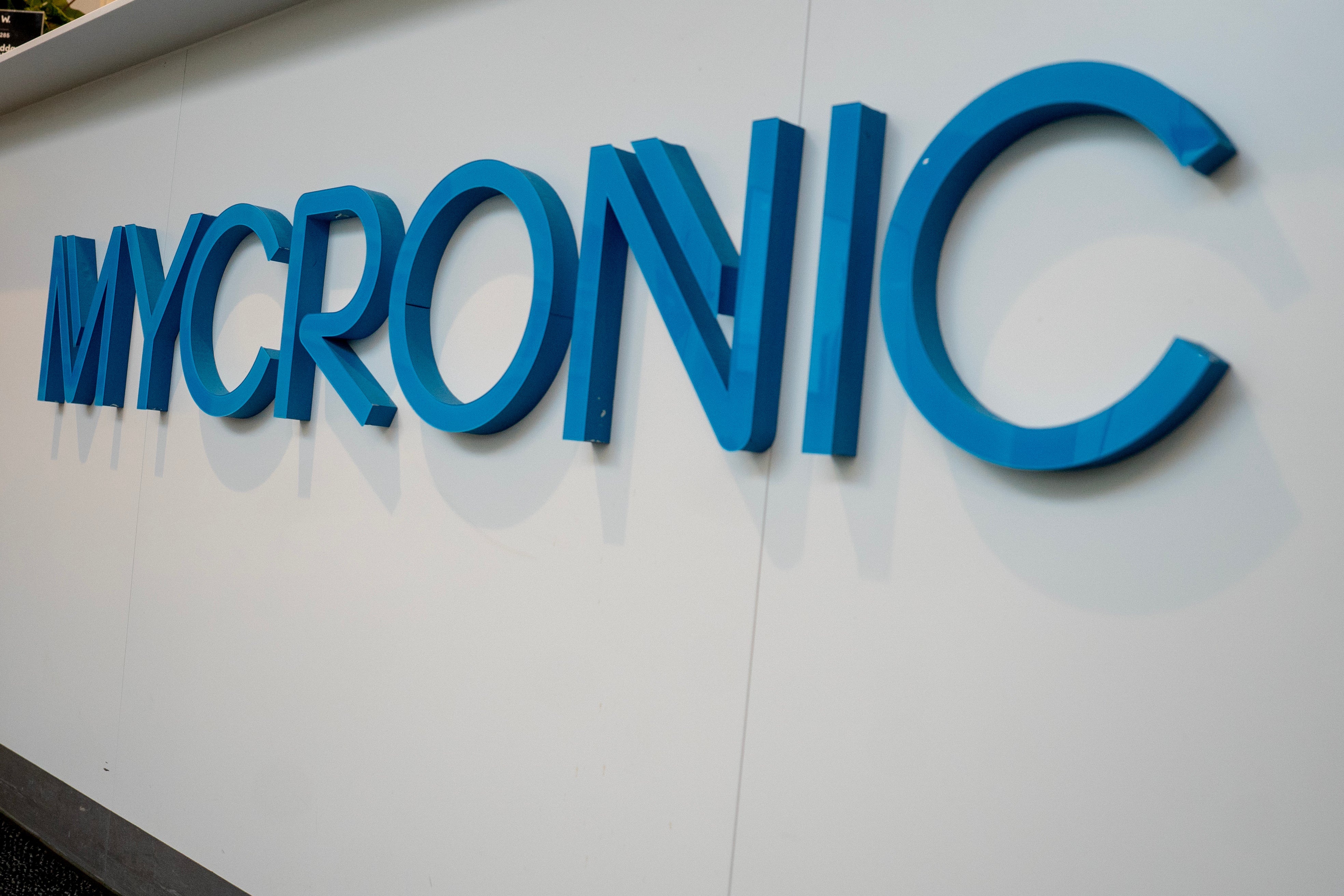 Blå skylt med texten MYCRONIC på vit vägg