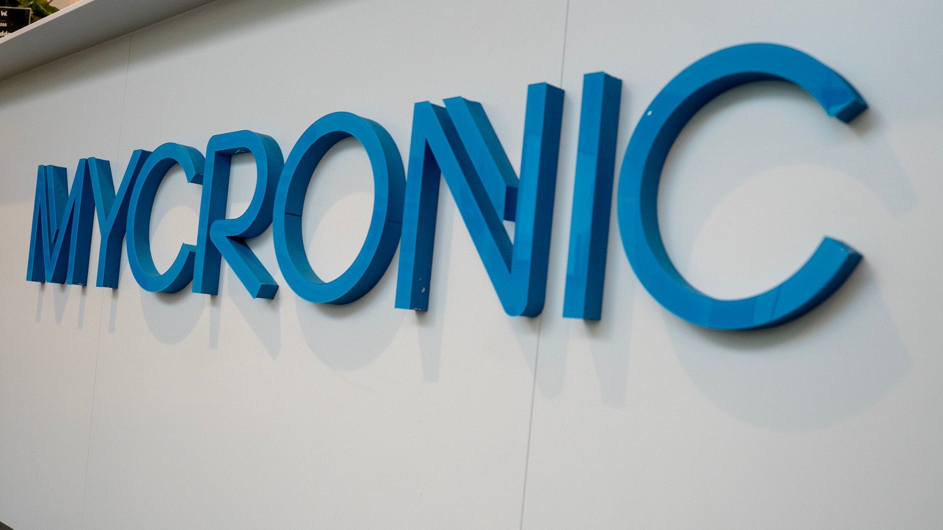 Blå skylt med texten MYCRONIC på vit vägg