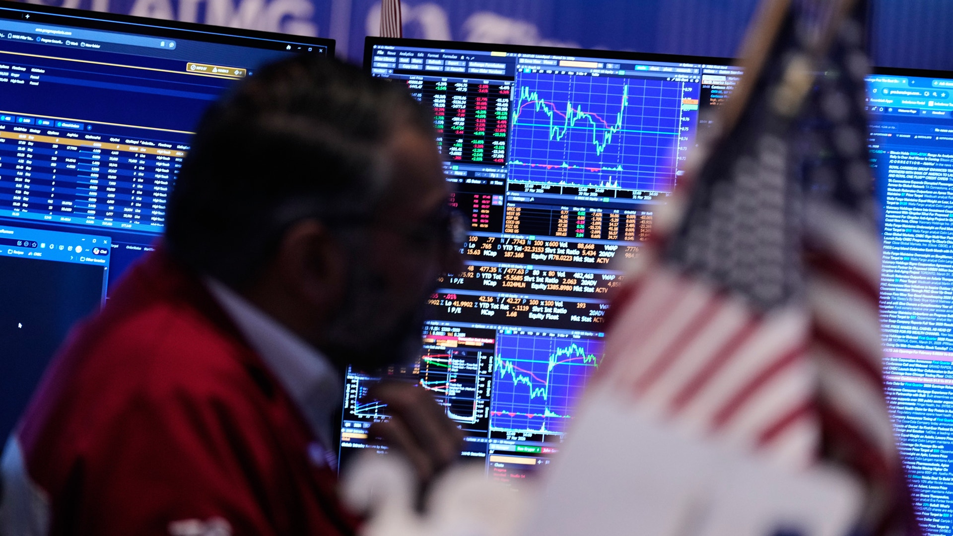 Person arbetar vid en finansiell handelsskärm med aktiemarknadsdata och diagram