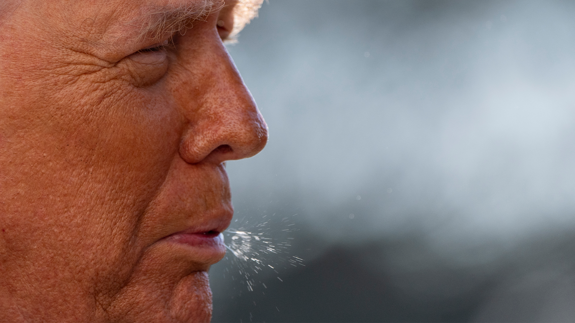 Närbild av en person i profilvy som blåser luft