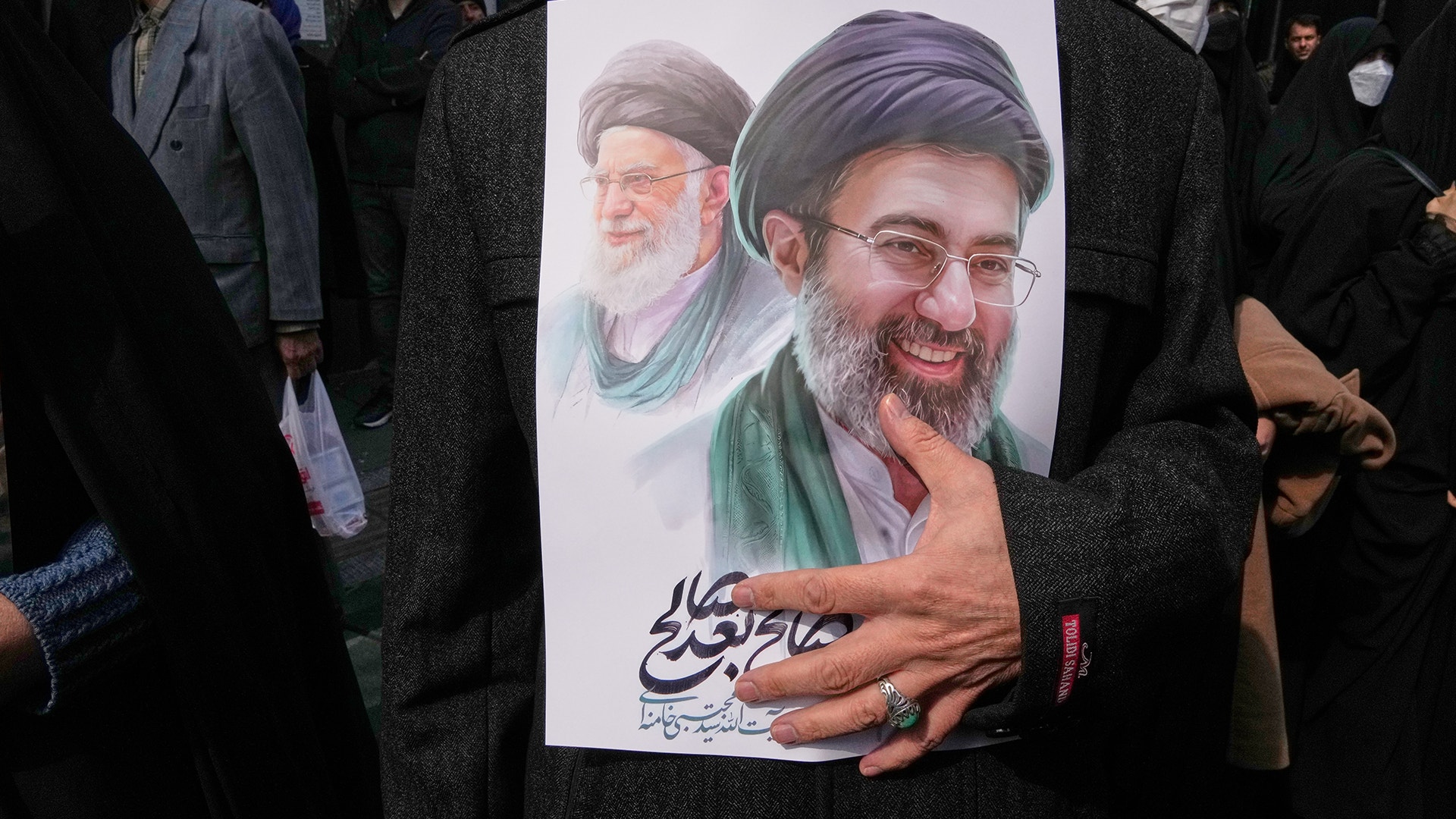 Människor håller upp en porträttaffisch vid en offentlig samling