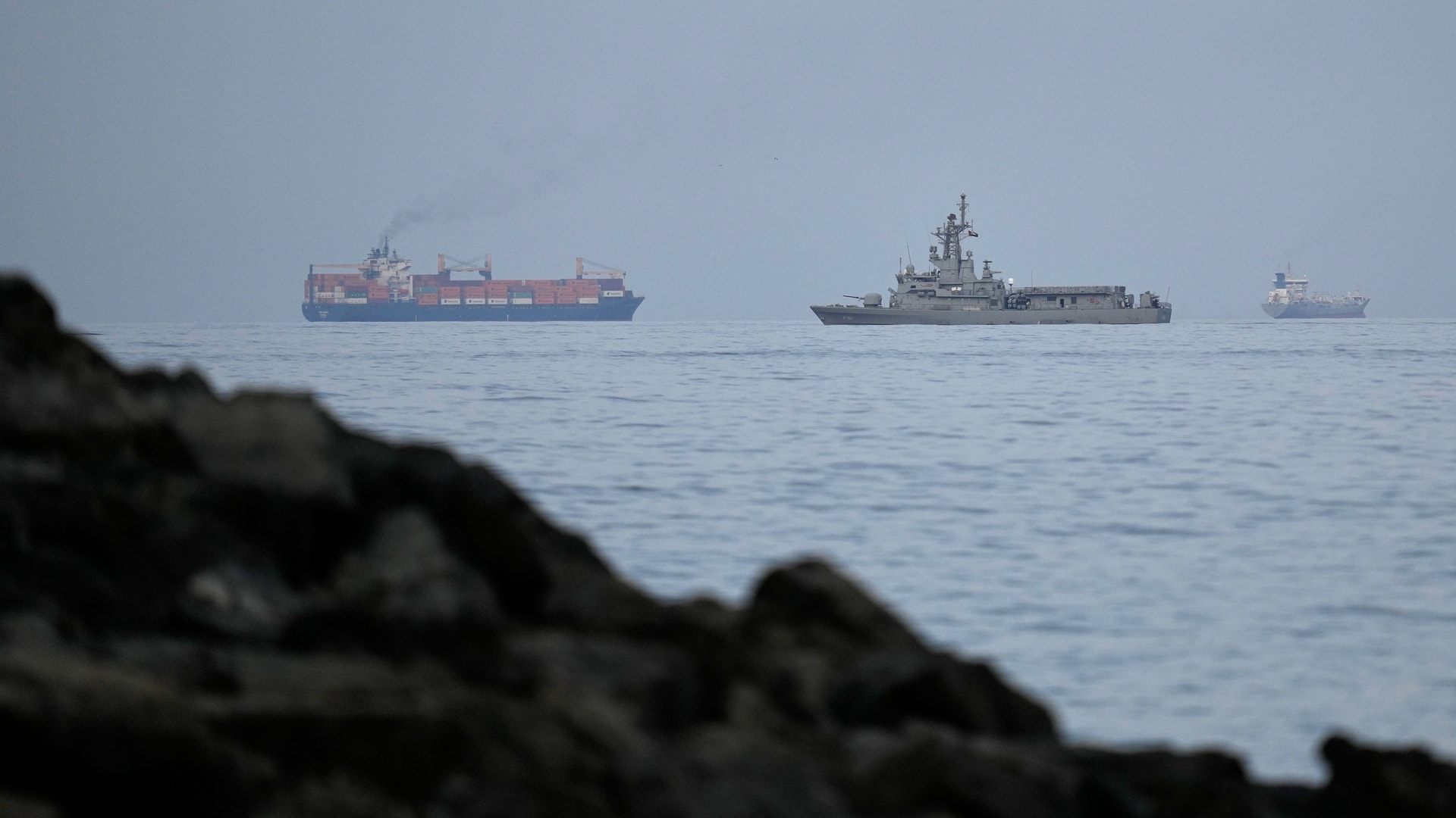 En marinbåt från Förenade Arabemiraten följer ett lastfartyg genom Hormuzsundet.