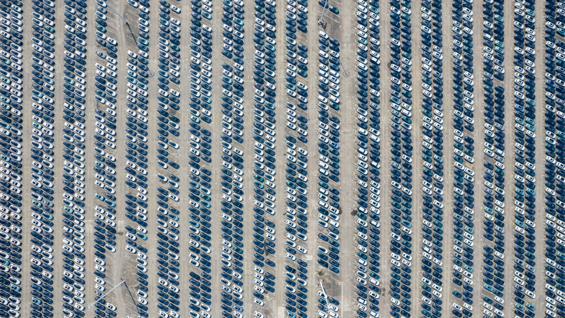 Flygfoto över en stor parkeringsplats med bilar parkerade i ordnade rader