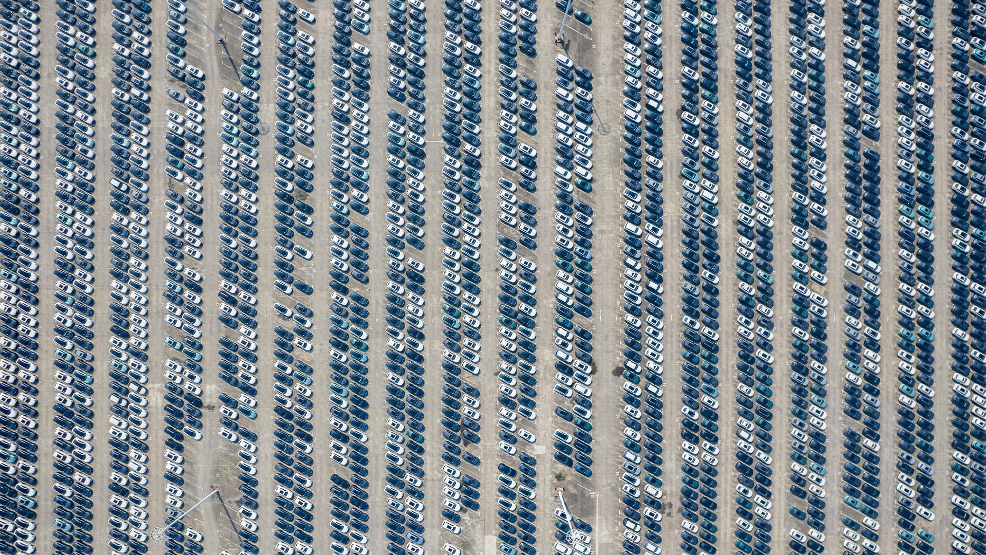 Flygfoto över en stor parkeringsplats med bilar parkerade i ordnade rader