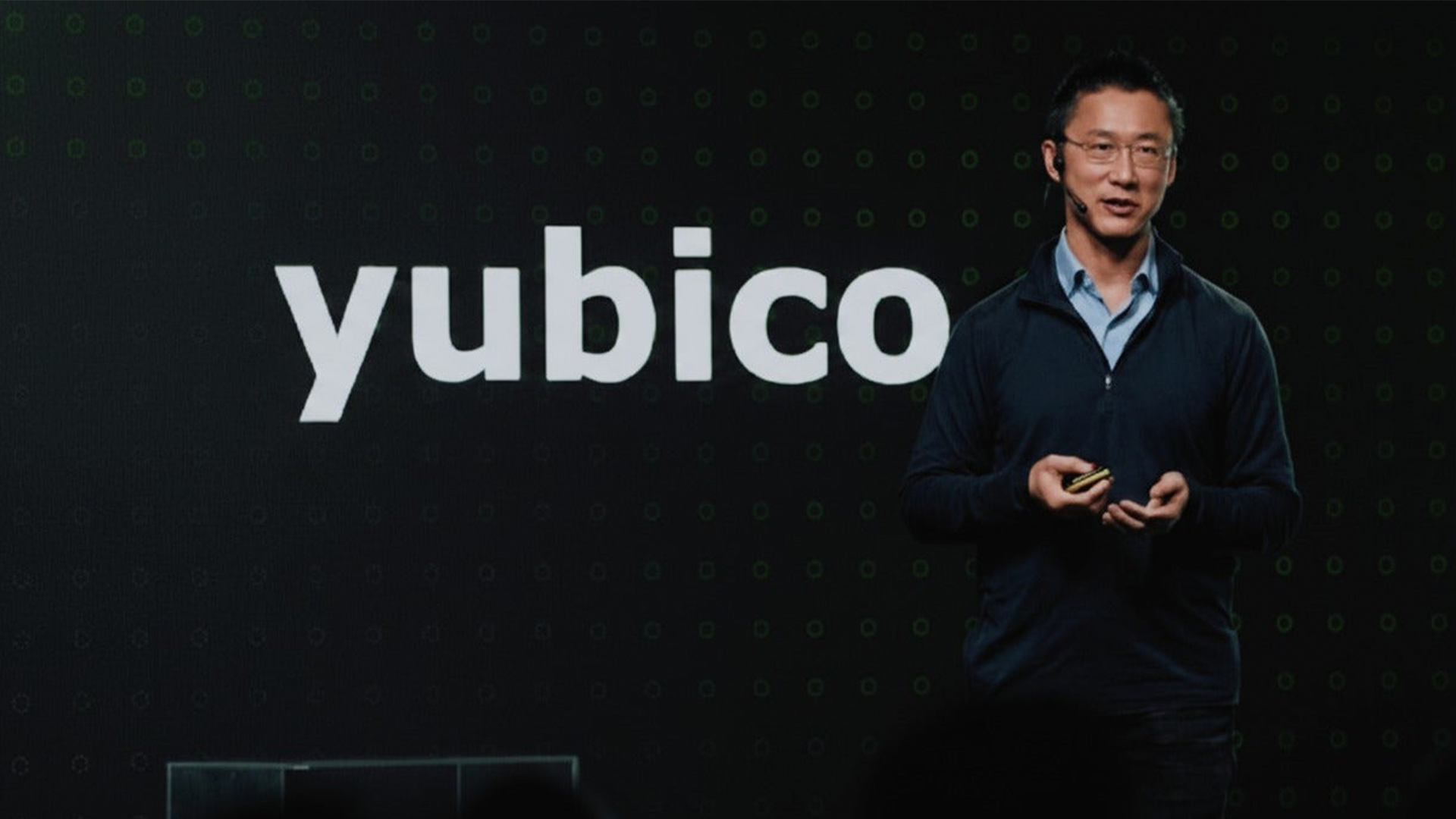 En person presenterar på scenen med Yubico-logotypen bakom sig.