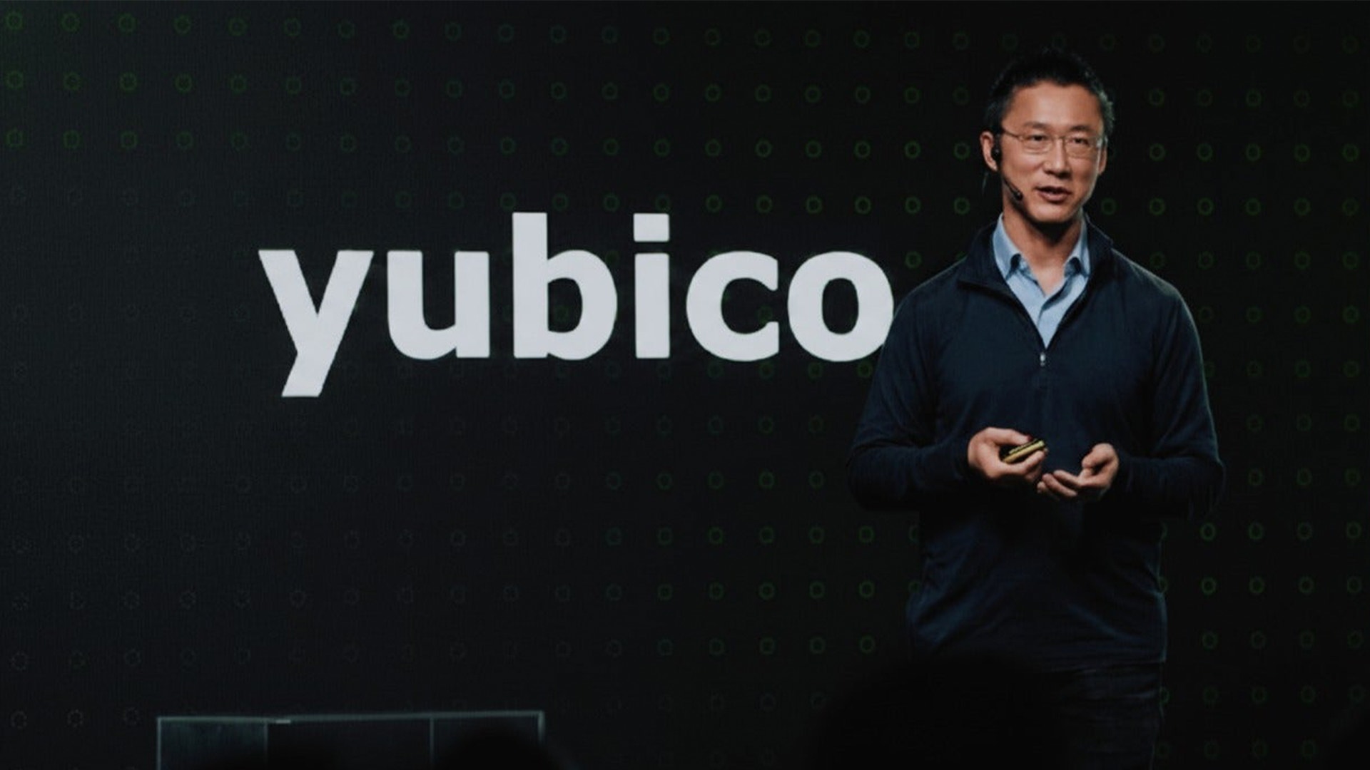 En person presenterar på scenen med Yubico-logotypen bakom sig.