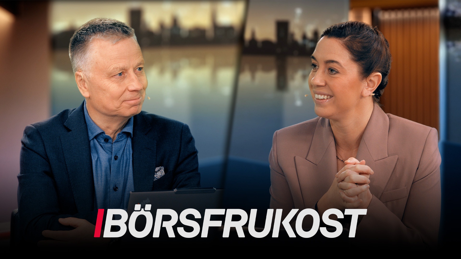 En man och en kvinna i affärskläder sitter och samtalar. Texten Börsfrukost visas längst ner på bilden.
