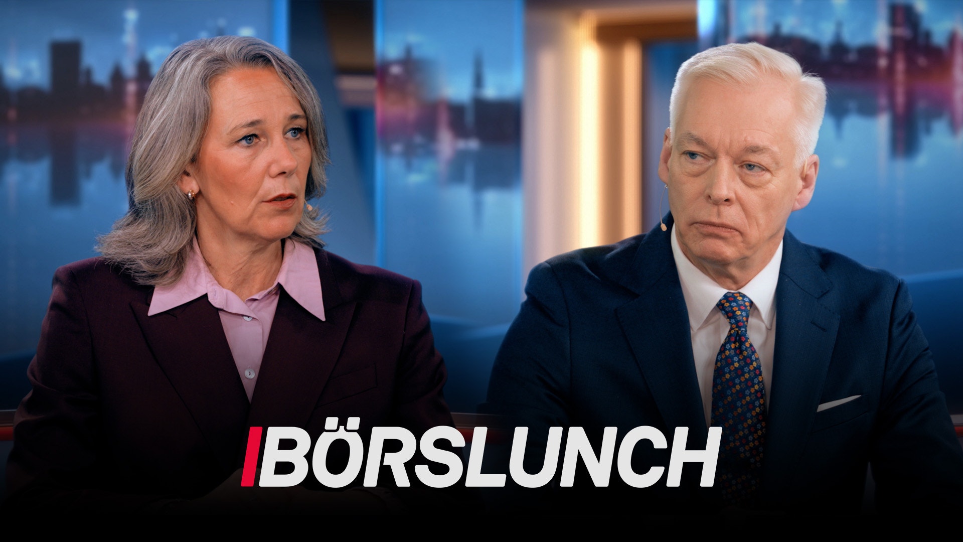 Två personer i affärskläder sitter framför en stadsskyline under en TV-sändning med texten Börslunch
