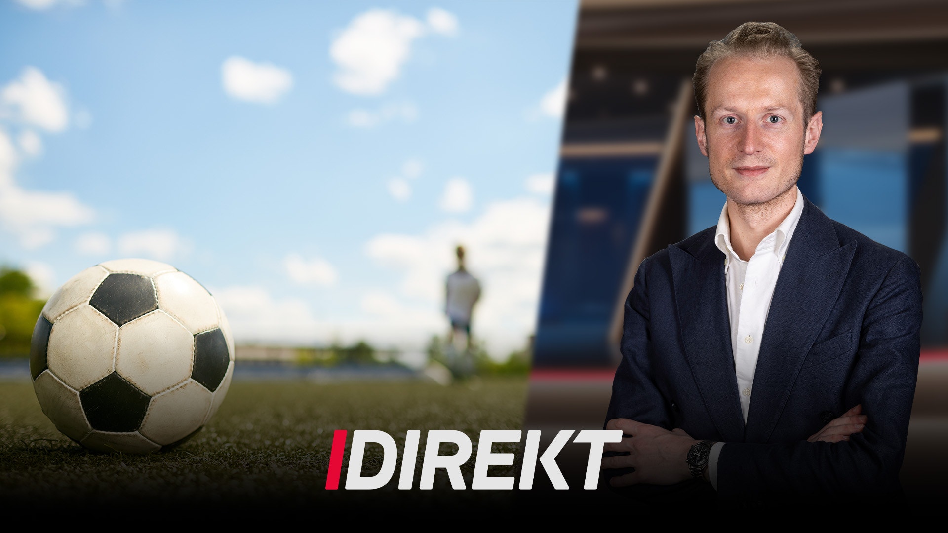 Man i kostym står bredvid en fotboll på gräsplan med stadion i bakgrunden