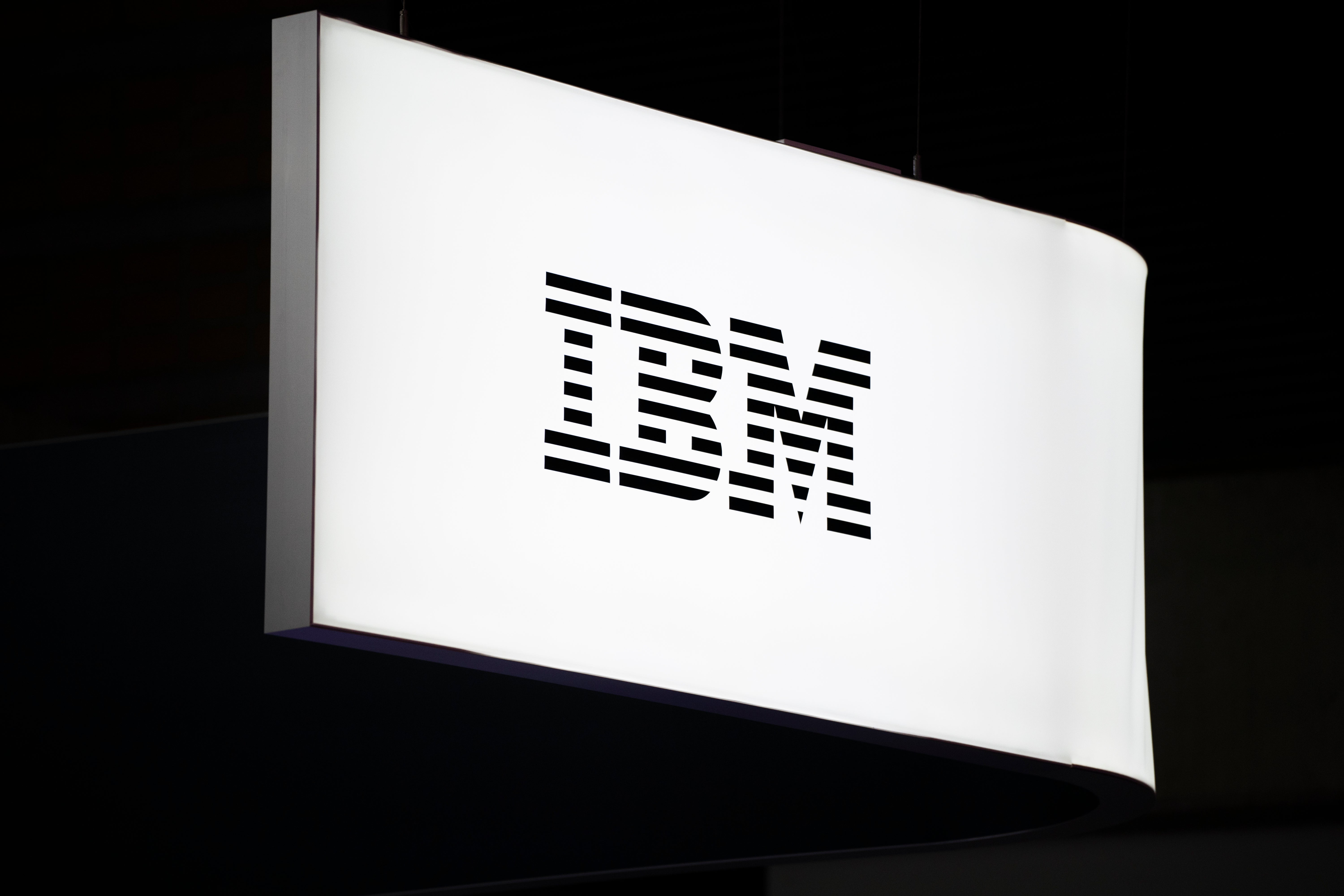 En vit belyst skylt med IBM-logotypen mot mörk bakgrund.